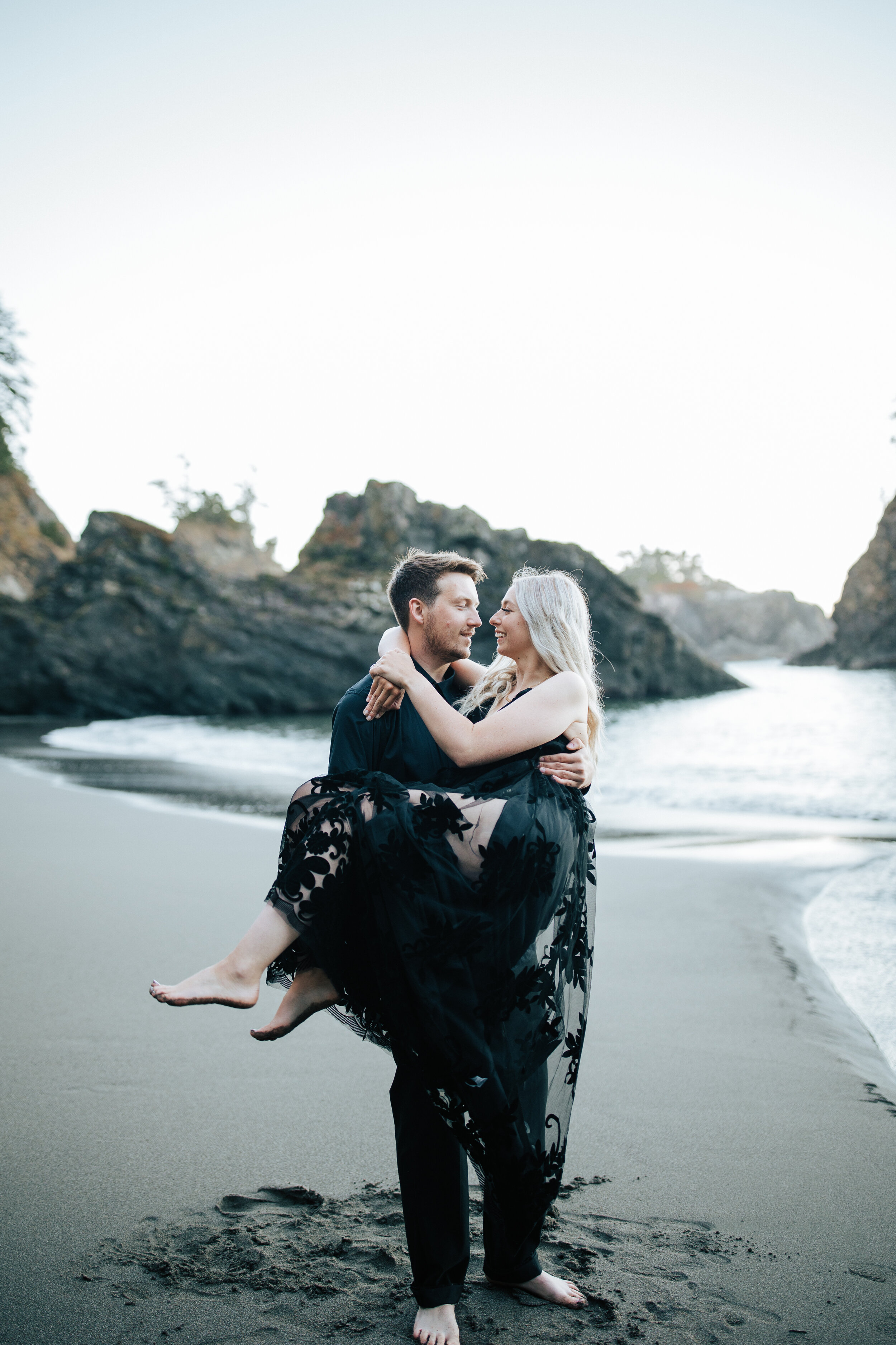  Samuel H Boardman Scenic Corridor southern Oregon coast elopement bride and groom saying their vows on a cliff on the Oregon coast with sea stacks and the ocean below black bridal gown couple in all black a groom carries his new bride on the beach #