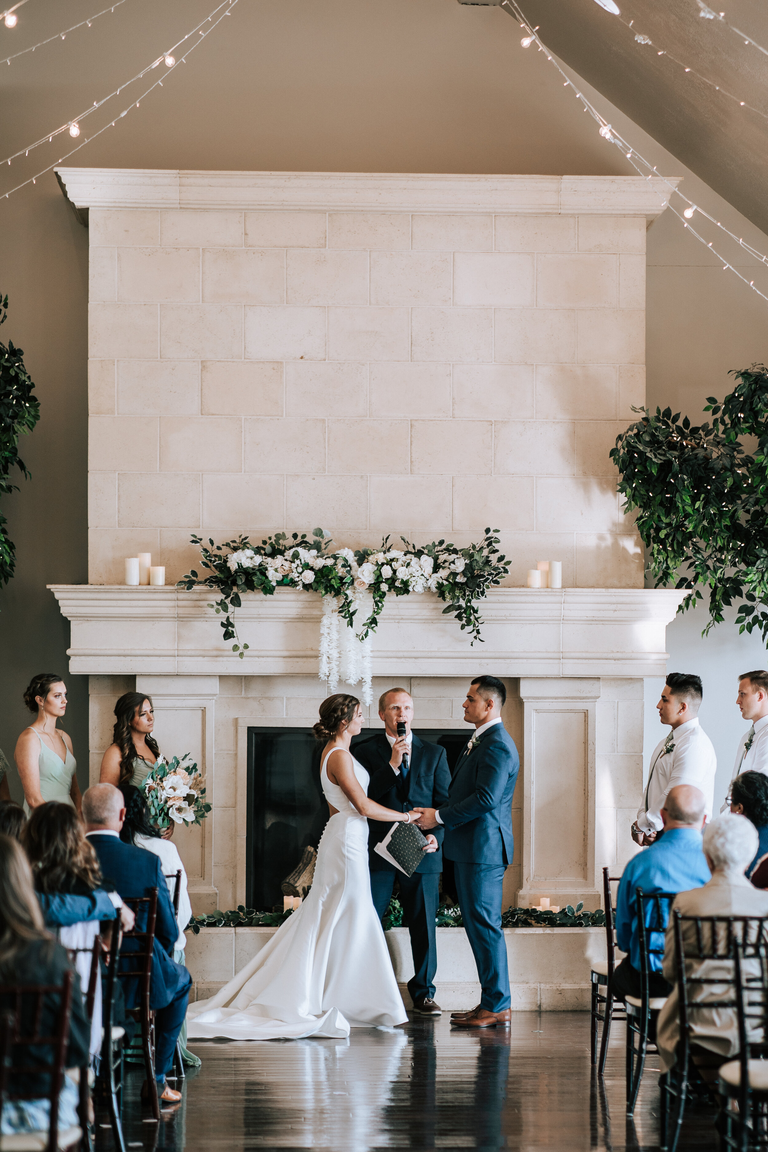 Stunning white marble fireplace is an altar for a couple holding hands with officiant speaking behind them by Emily Jenkins Photography at Sleepy Ridge in Orem. stunning indoor wedding venues in Utah mr and mrs #emilyjenkinsphotography #emilyjenkins