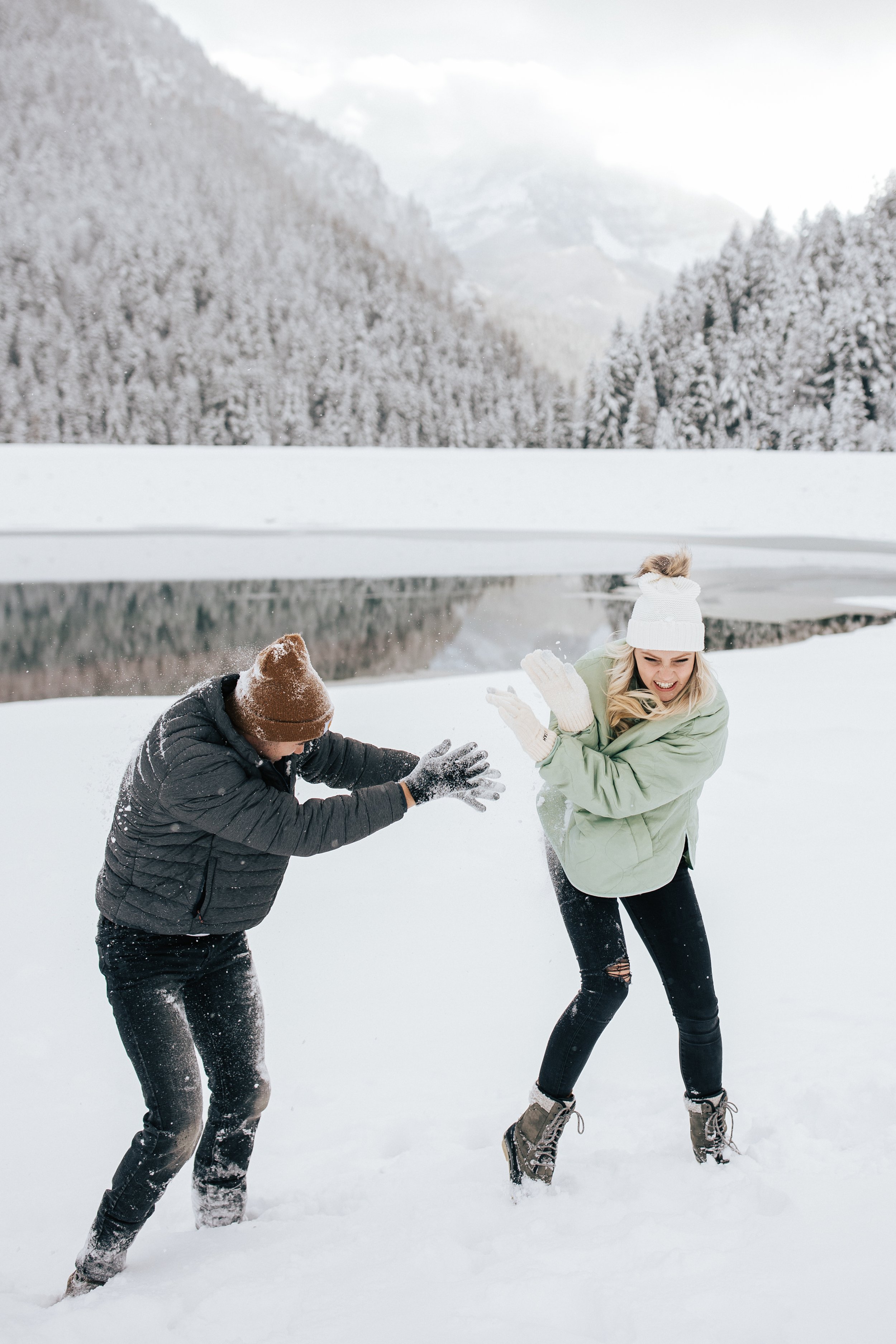 Couples has snowball fight in the Utah mountains during winter #winteroutfitinspo #winterphotoshoot #winterengagements #parkcityengagements Utah photographer