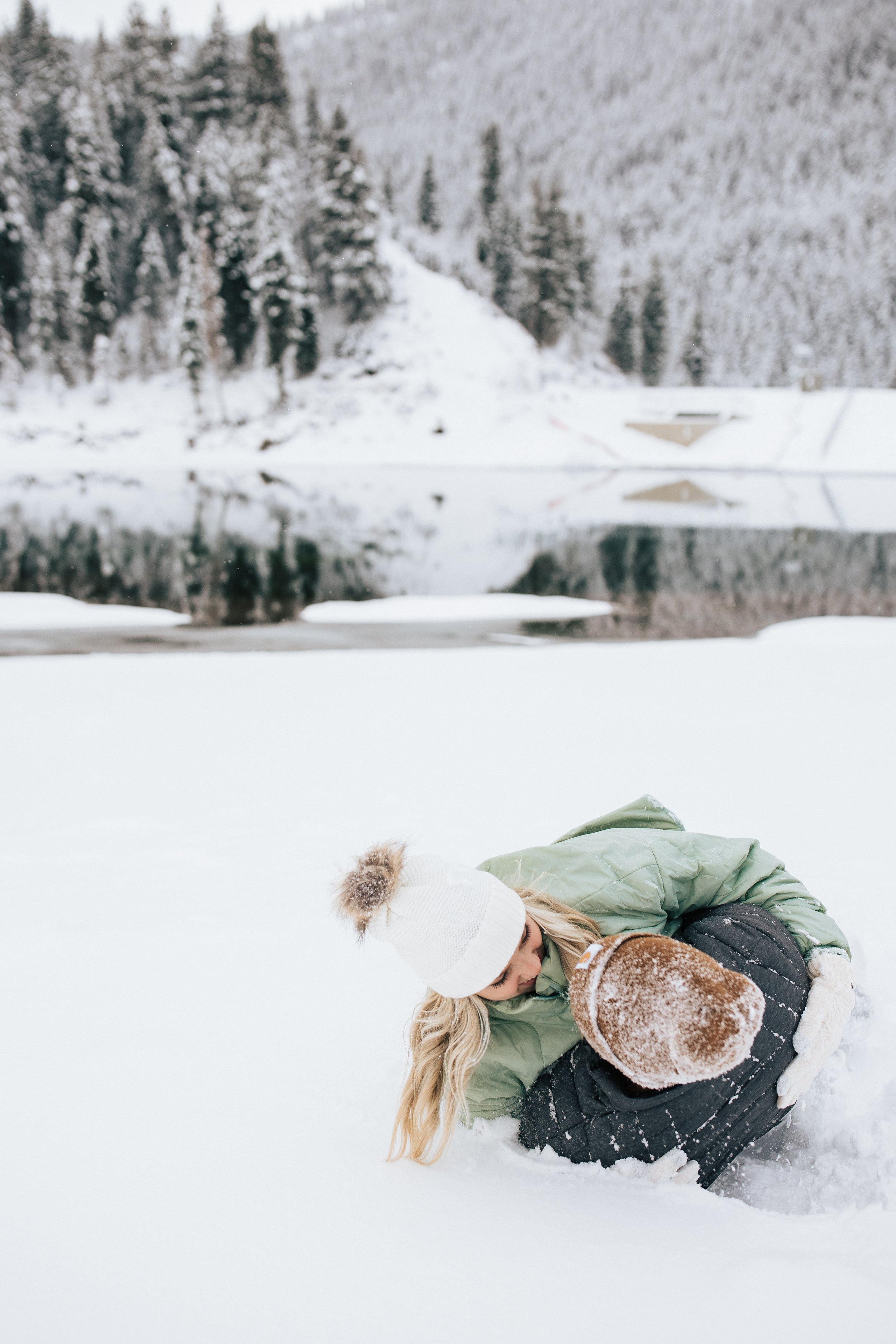  Snowball fight during couples photoshoot in the Utah mountains couple hugs as it's snowing covered in snowflakes engagement session winter outfit inspo #outfitinspo #parkcityphotographer #engagements #winterengagements couple rolling around in snow 