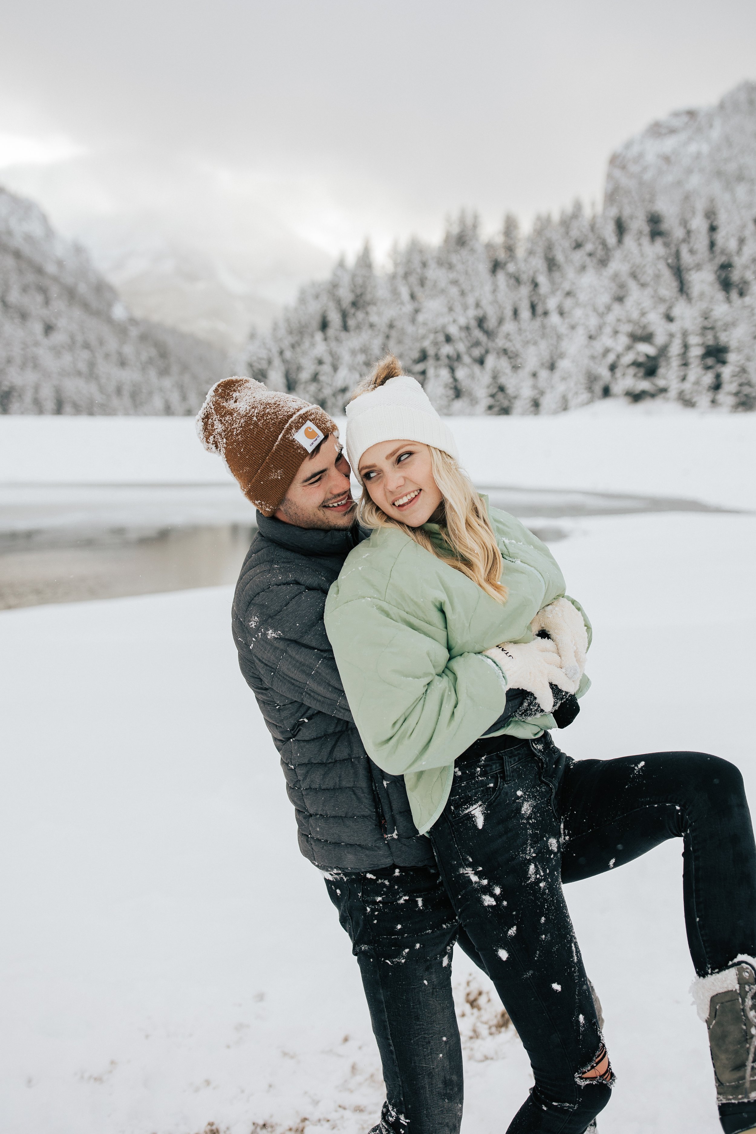  Snowball fight during couples photoshoot in the Utah mountains couple hugs as it's snowing covered in snowflakes engagement session winter outfit inspo #outfitinspo #parkcityphotographer #engagements #winterengagements  