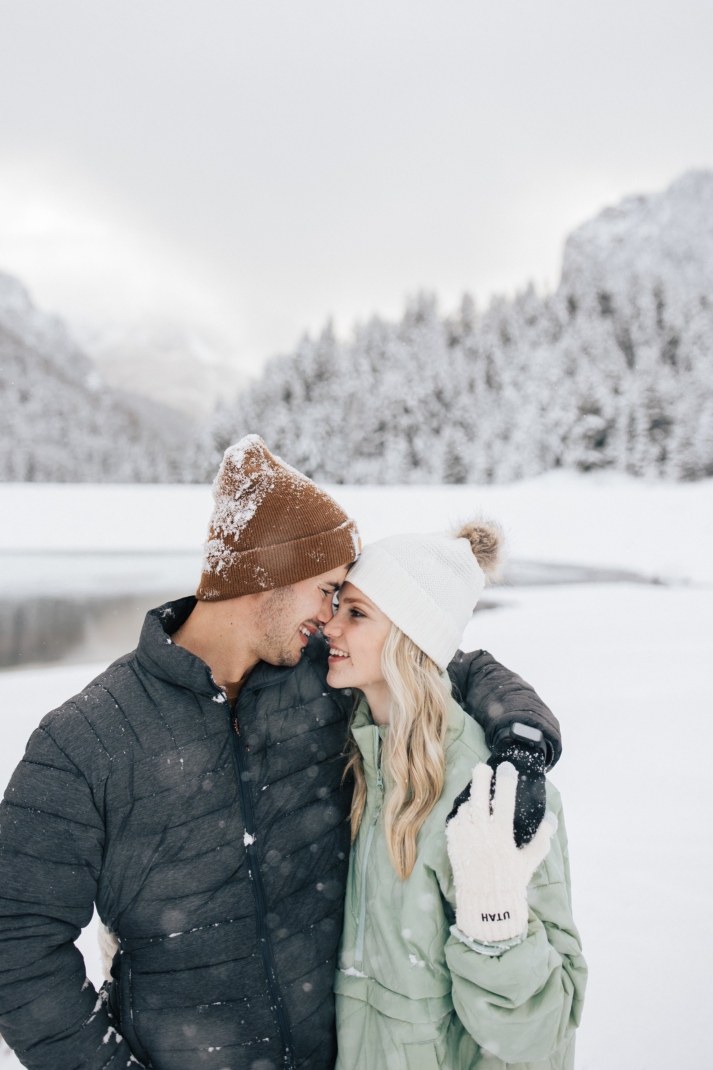  Snowball fight during couples photoshoot in the Utah mountains couple hugs as it's snowing covered in snowflakes engagement session winter outfit inspo #outfitinspo #parkcityphotographer #engagements #winterengagements 