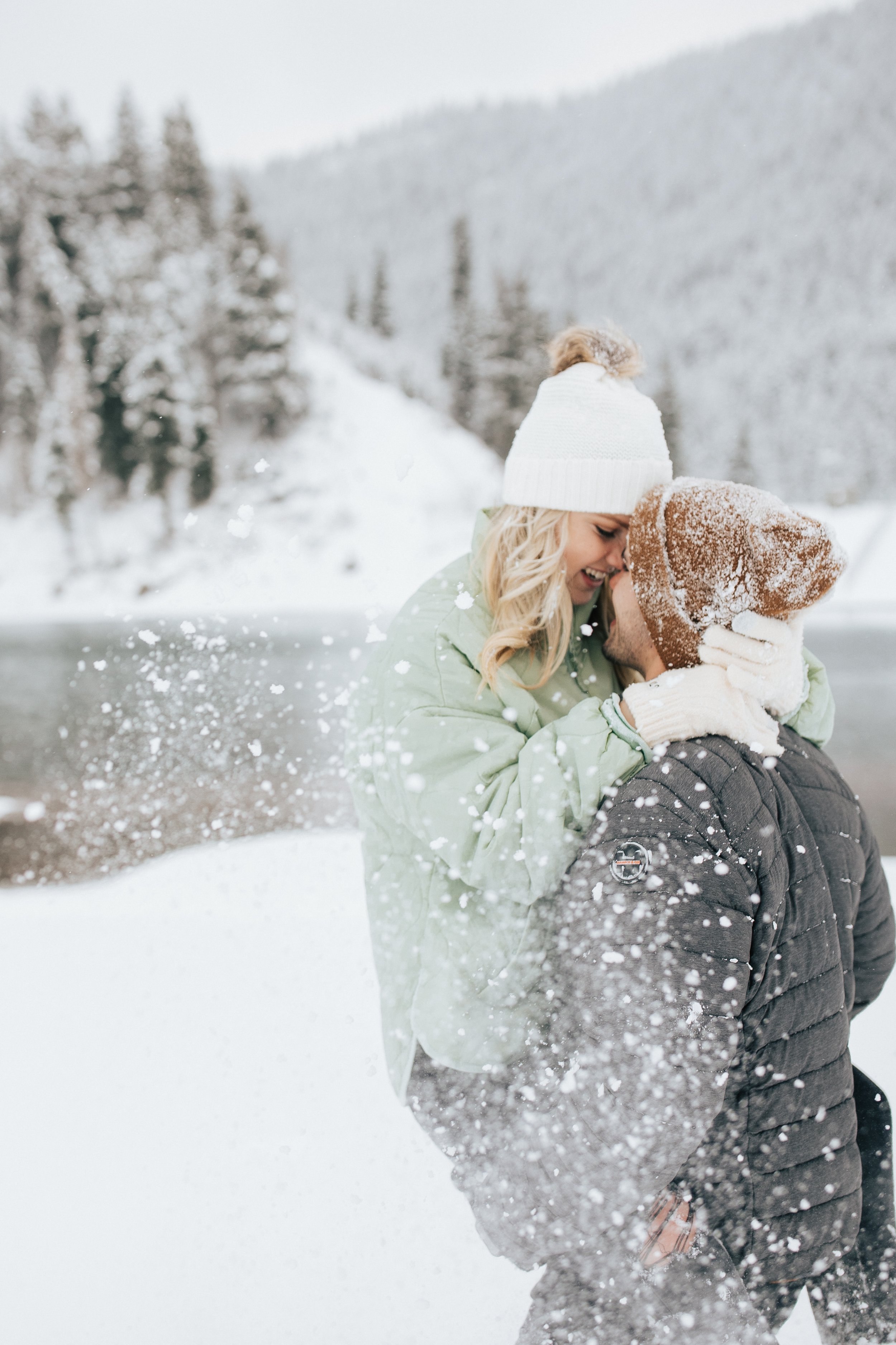  Snowball fight during couples photoshoot in the Utah mountains couple hugs as it's snowing covered in snowflakes engagement session winter outfit inspo #outfitinspo #parkcityphotographer #engagements #winterengagements 