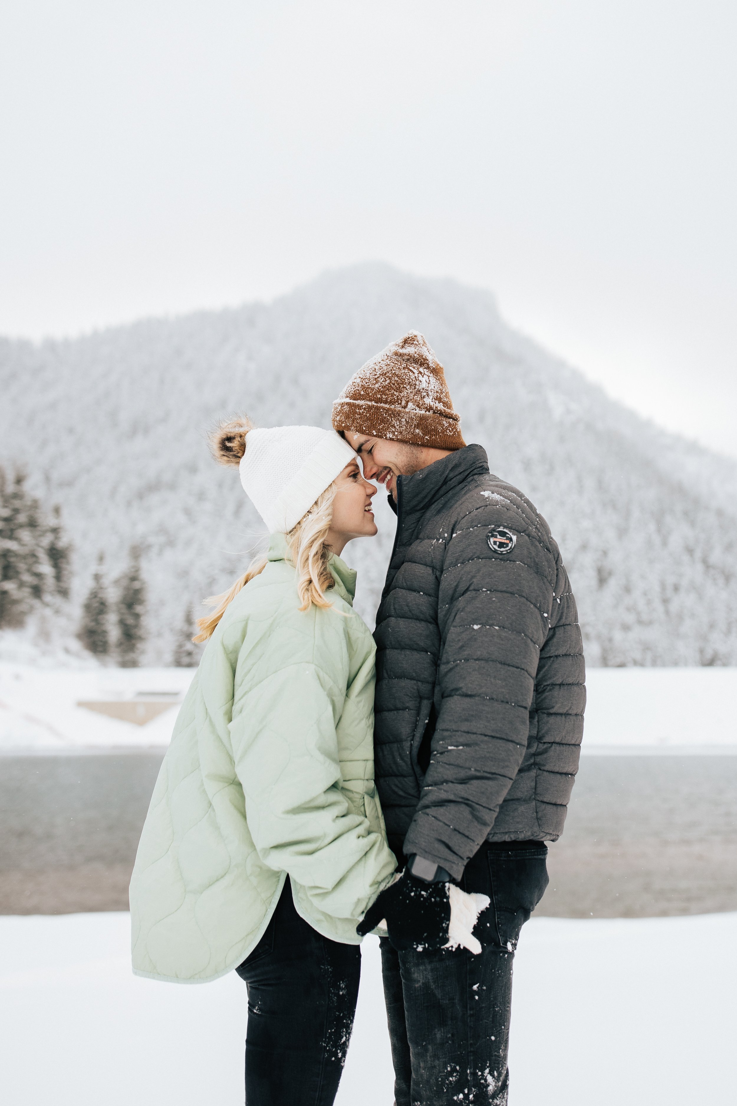  Snowball fight during couples photoshoot in the Utah mountains couple hugs as it's snowing covered in snowflakes engagement session winter outfit inspo #outfitinspo #parkcityphotographer #engagements #winterengagements snow covered pine trees 