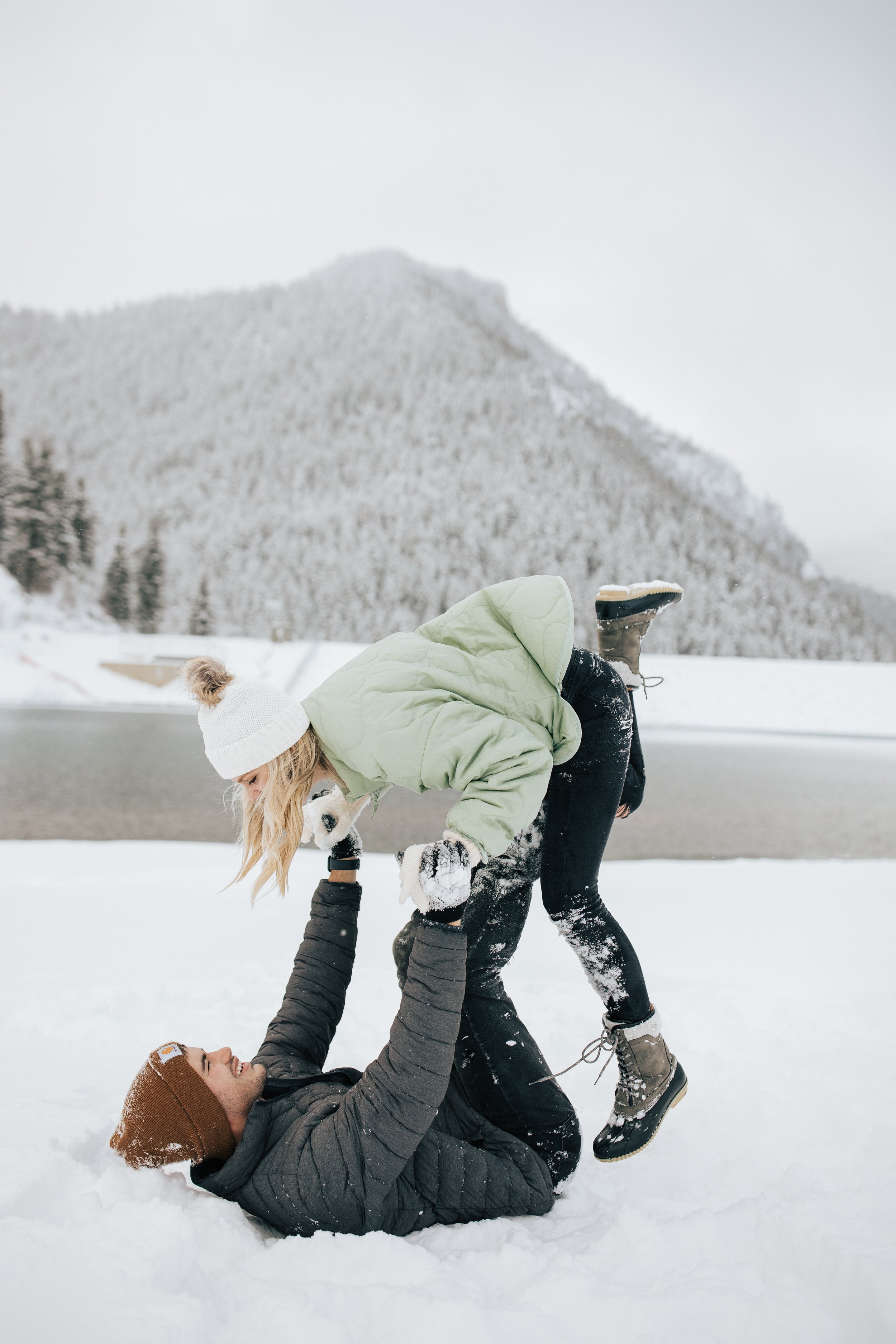  Snowball fight during couples photoshoot in the Utah mountains couple hugs as it's snowing covered in snowflakes engagement session winter outfit inspo #outfitinspo #parkcityphotographer #engagements #winterengagements 