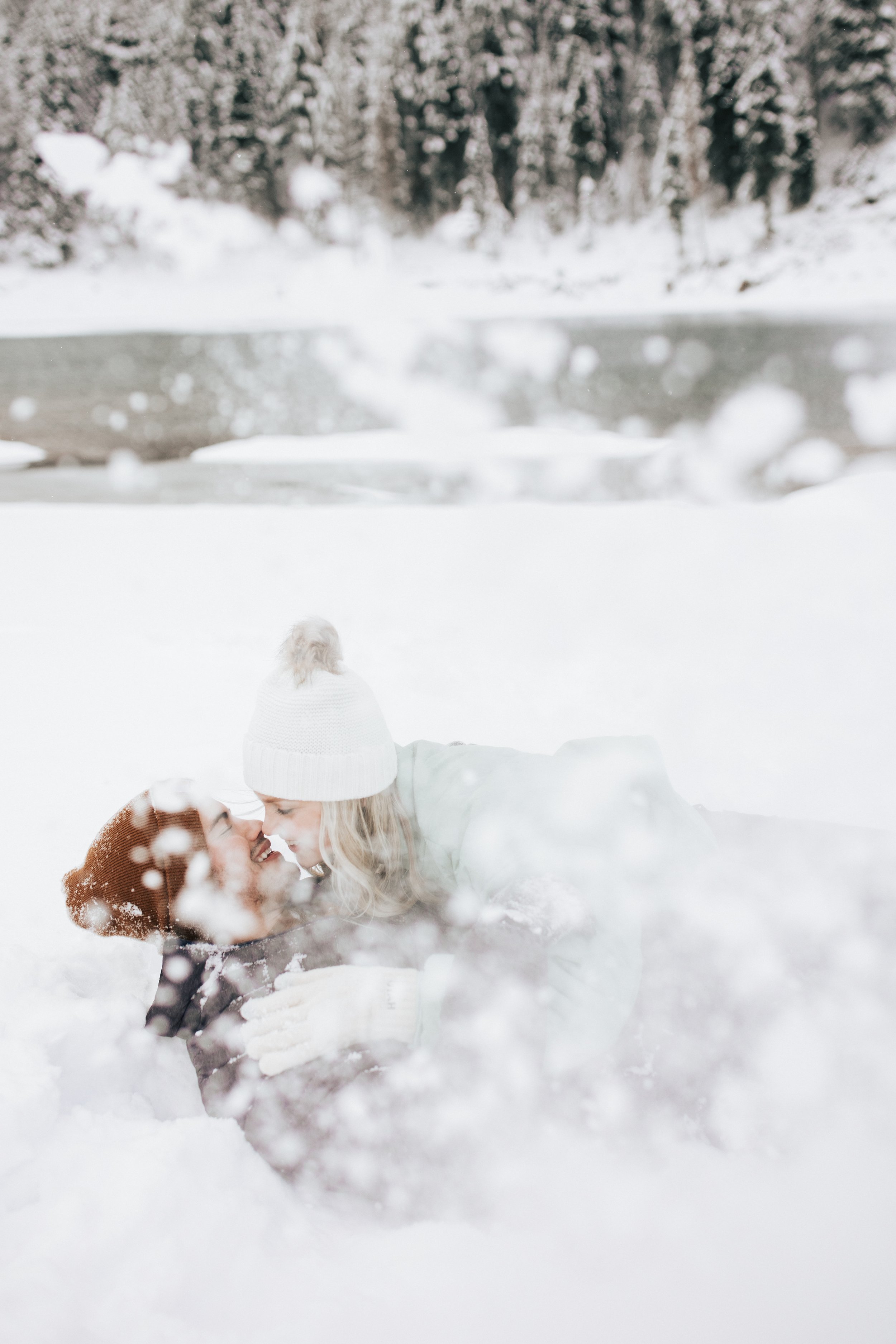  Snowball fight at winter engagement session photoshoot in the Utah mountains couple hugs as it's snowing covered in snowflakes engagement session winter outfit inspo #outfitinspo #parkcityphotographer #engagements #winterengagements 