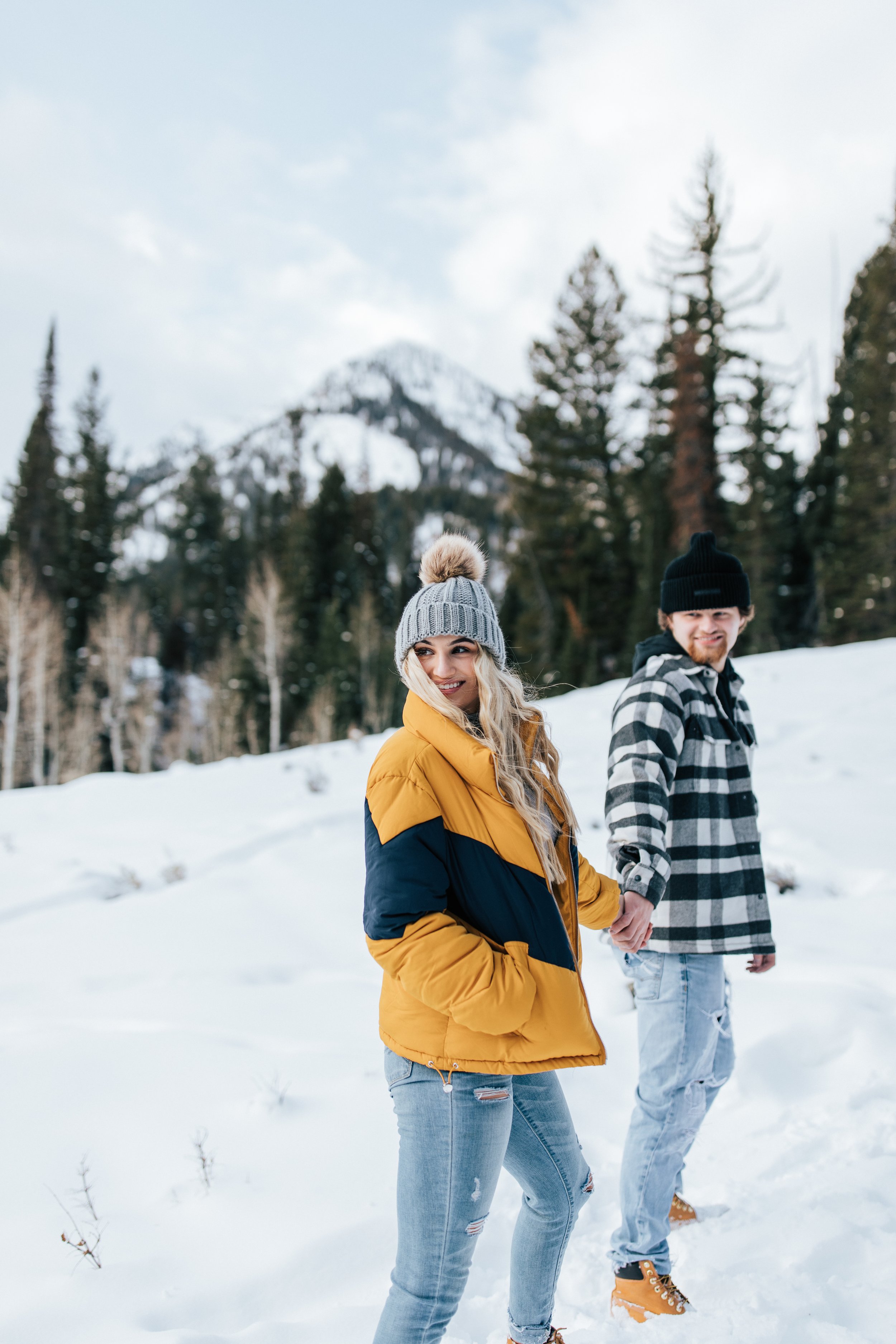  Winter photoshoot outfit inspo man holds his fiance in the mountains around pine trees and snow couples session couple playing in the snow winter engagement session #winteroutfitinspo #outfitinspo #winteroutfits #winterphotoshoot yellow coat 
