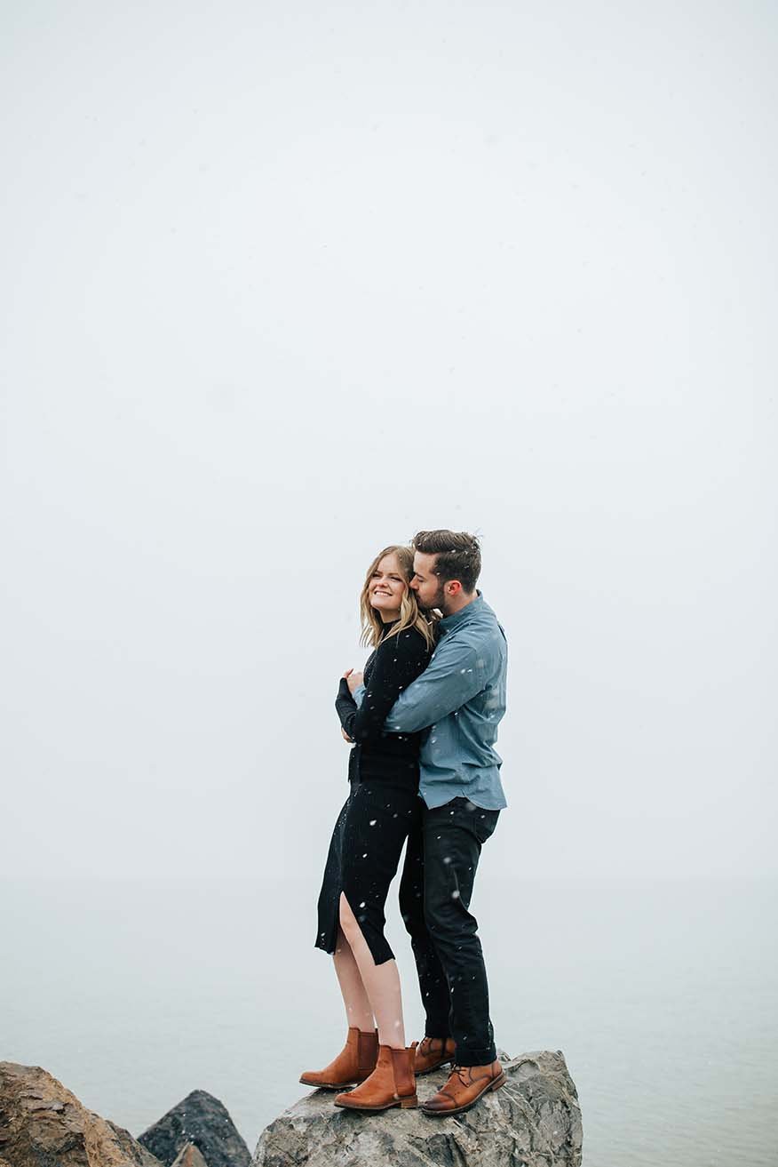  Winter photoshoot outfit inspo man holds his fiance in the mountains around pine trees and snow couples session couple playing in the snow winter engagement session #winteroutfitinspo #outfitinspo #winteroutfits #winterphotoshoot  