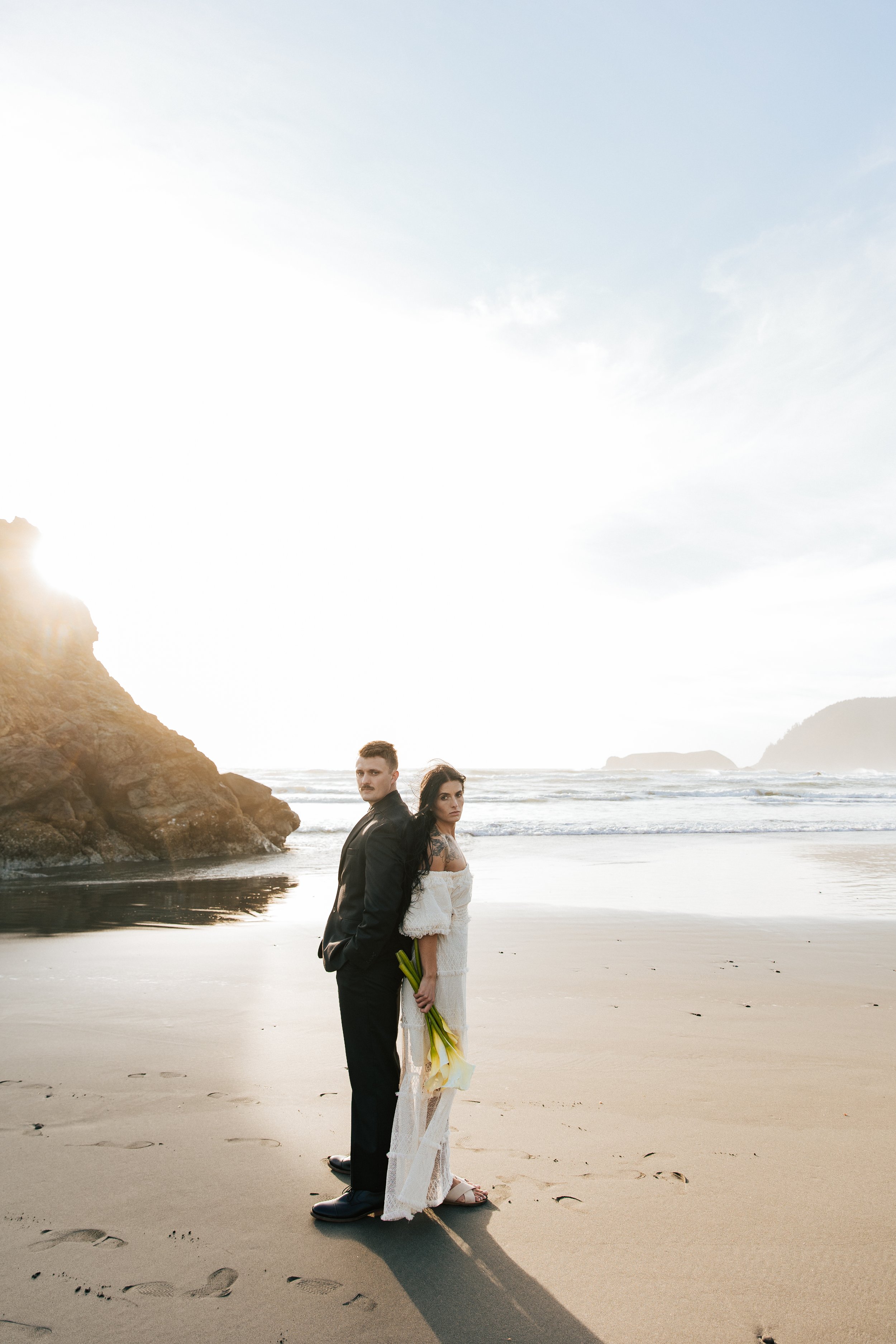  Oregon coast elopement. Couple elopes on the beach with the sun shining behind them. Sun rays behind rocks. Beach with rocks and haystacks. Southern Oregon. Brookings, Oregon. Samuel H Boardman elopement. #oregon #photographer #elopement Couple stan