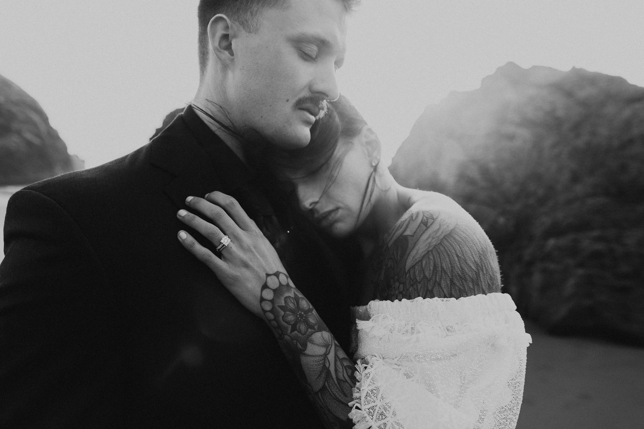  Oregon coast elopement. Couple elopes on the beach with the sun shining behind them. Sun rays behind rocks. Beach with rocks and haystacks. Southern Oregon. Black and white photo of couple cuddling. Brookings, Oregon. Samuel H Boardman elopement. #o