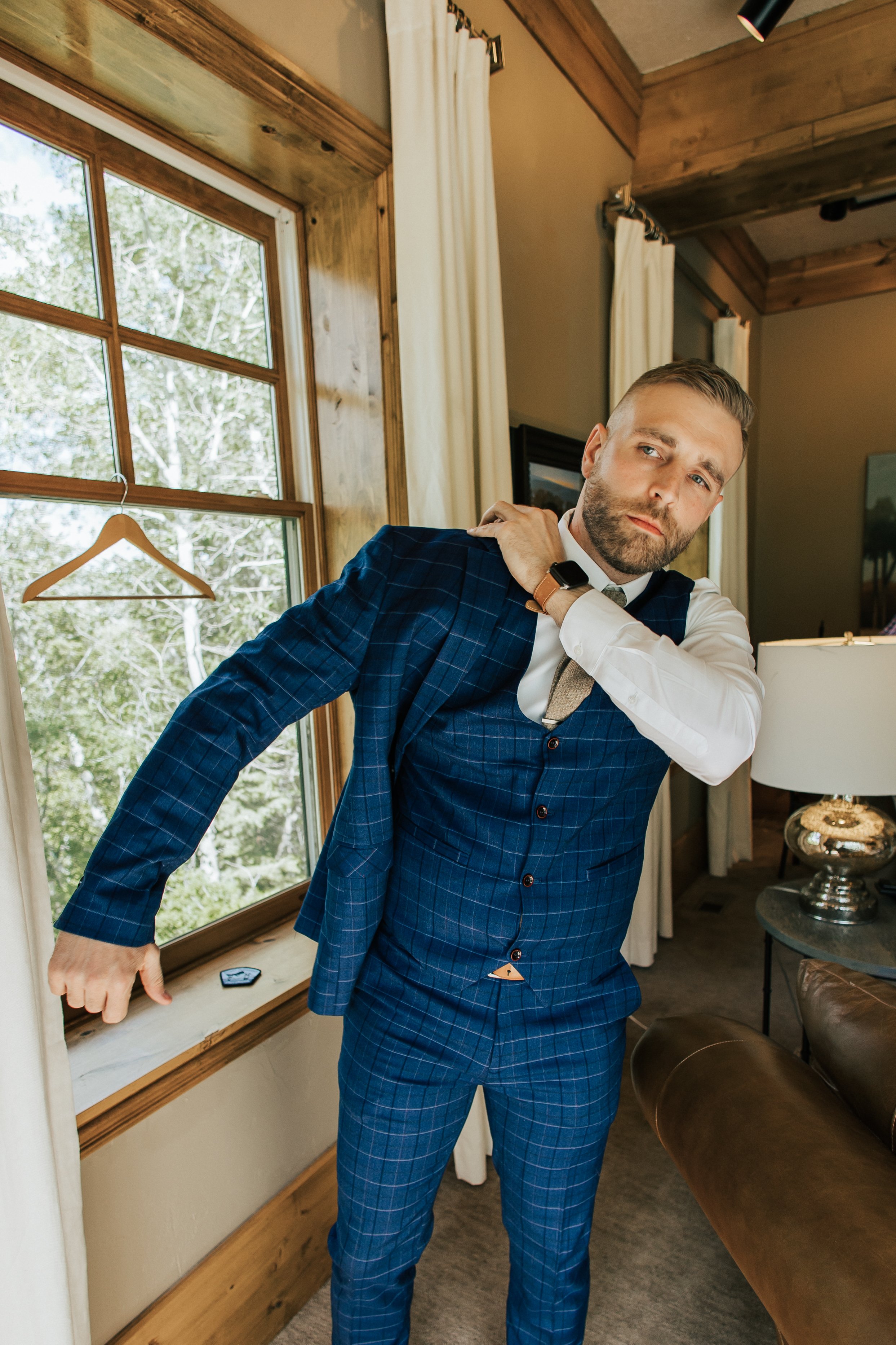  Groom putting on his suit while getting ready for his wedding ceremony in Sundance, Utah Provo Canyon. Summer wedding. 