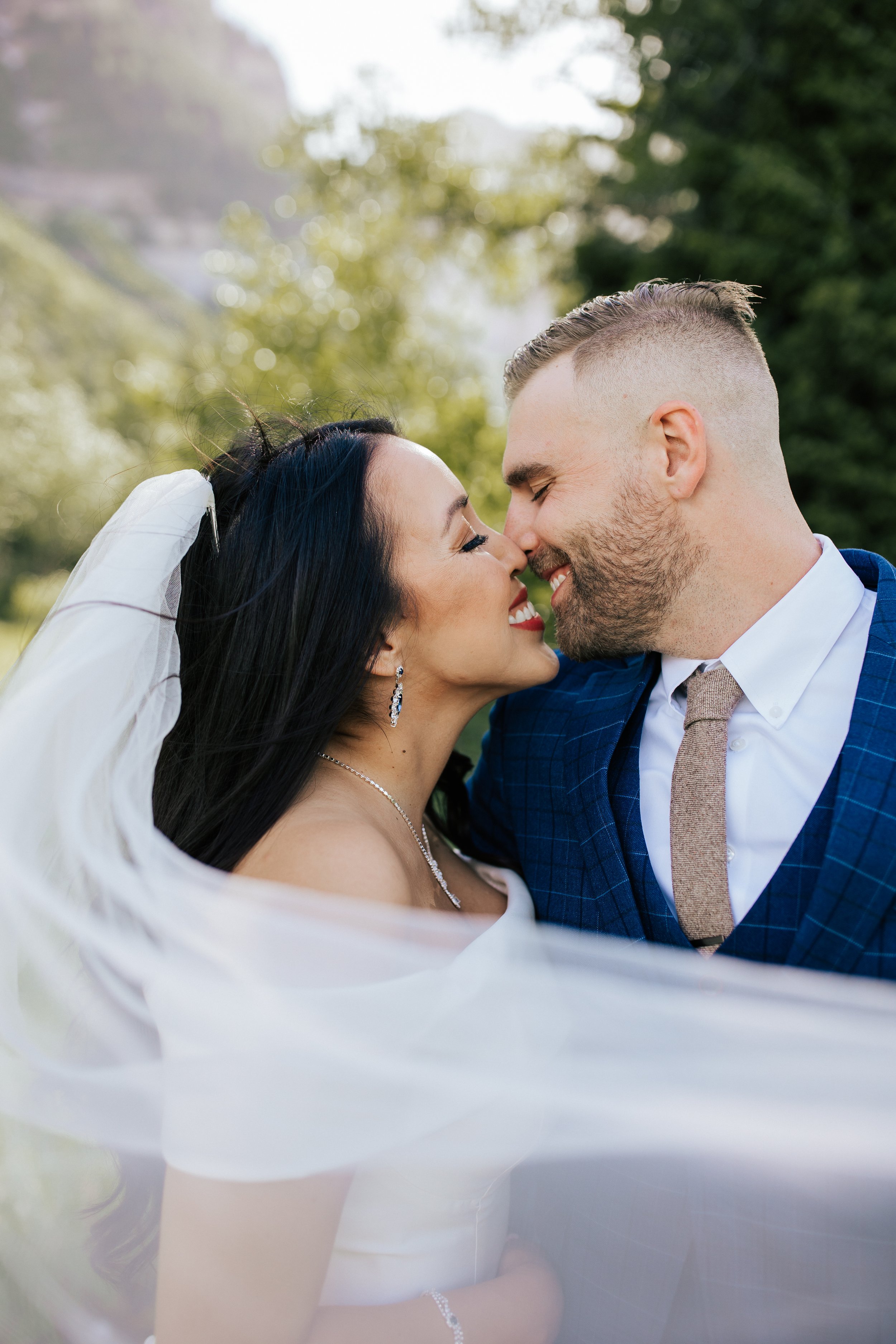  Portrait session with bride and groom before their wedding ceremony in Aspen Grove, Provo Canyon, Utah. Bride’s long veil is draped in the photo frame while bride and groom kiss. #weddingdress #firstlook #bridalportraits 