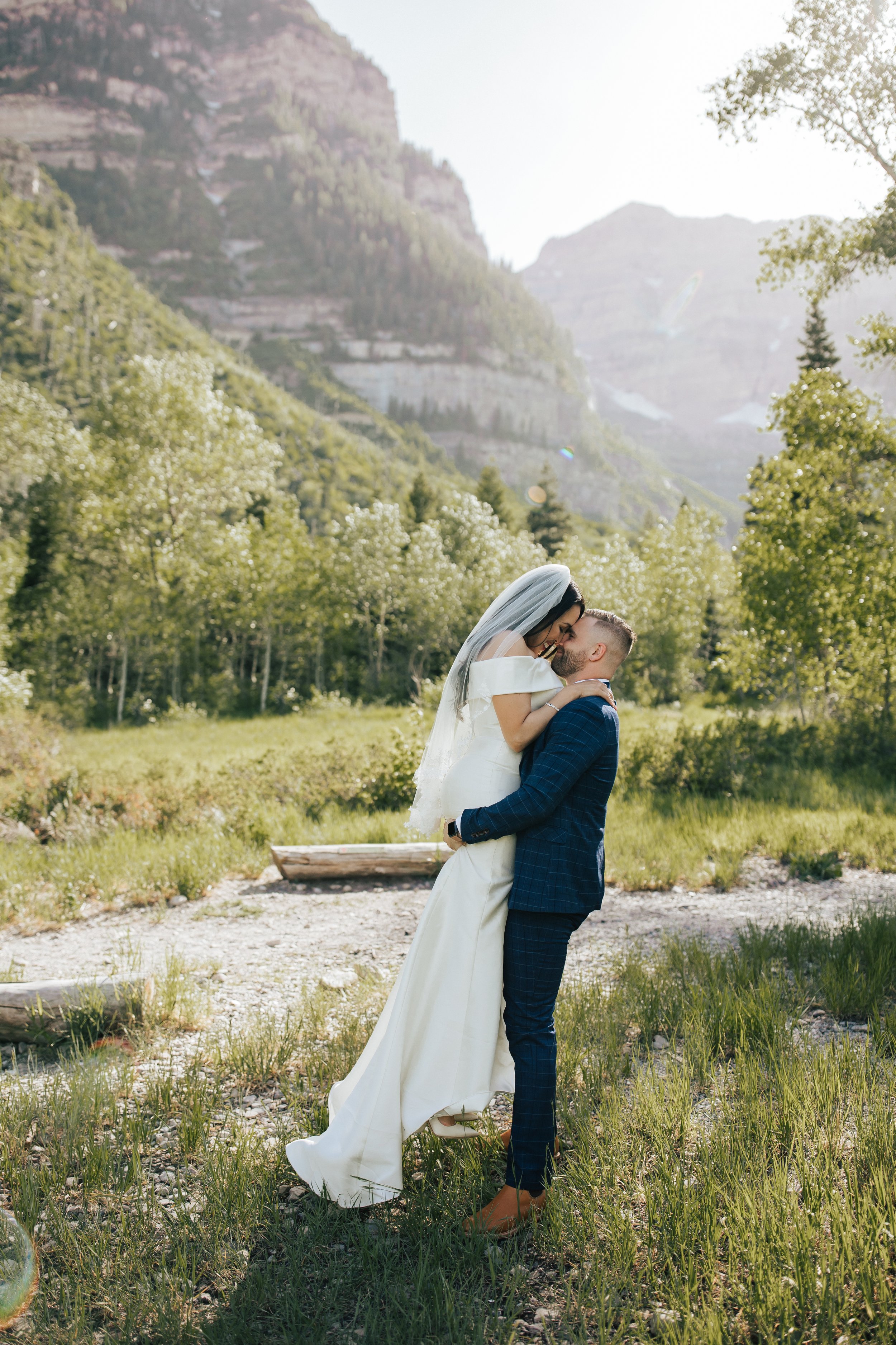  Groom lifts up his bride as they kiss in the mountains as sunset. First look session with bride and groom before their wedding ceremony in Aspen Grove, Provo Canyon, Utah. Bride and groom portraits. #weddingdress #firstlook #bridalportraits 