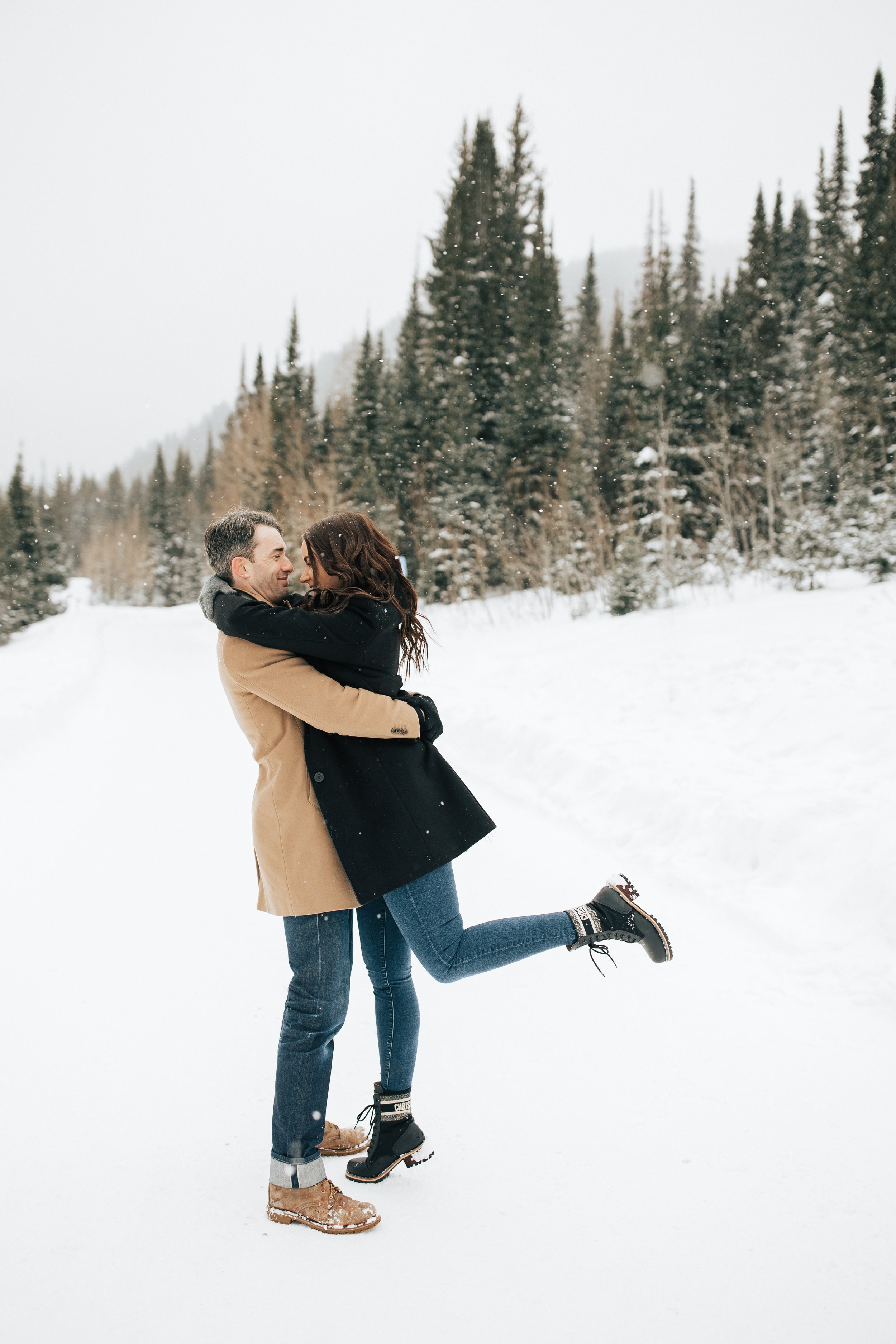  Winter photoshoot outfit inspo. Man and woman kiss in the snowy mountains wearing coats and beanies. Utah mountain engagement shoot in the winter. Park City, Utah photographer. #winter #engagements #engagementsession #utahphotoshoot #utahengagements