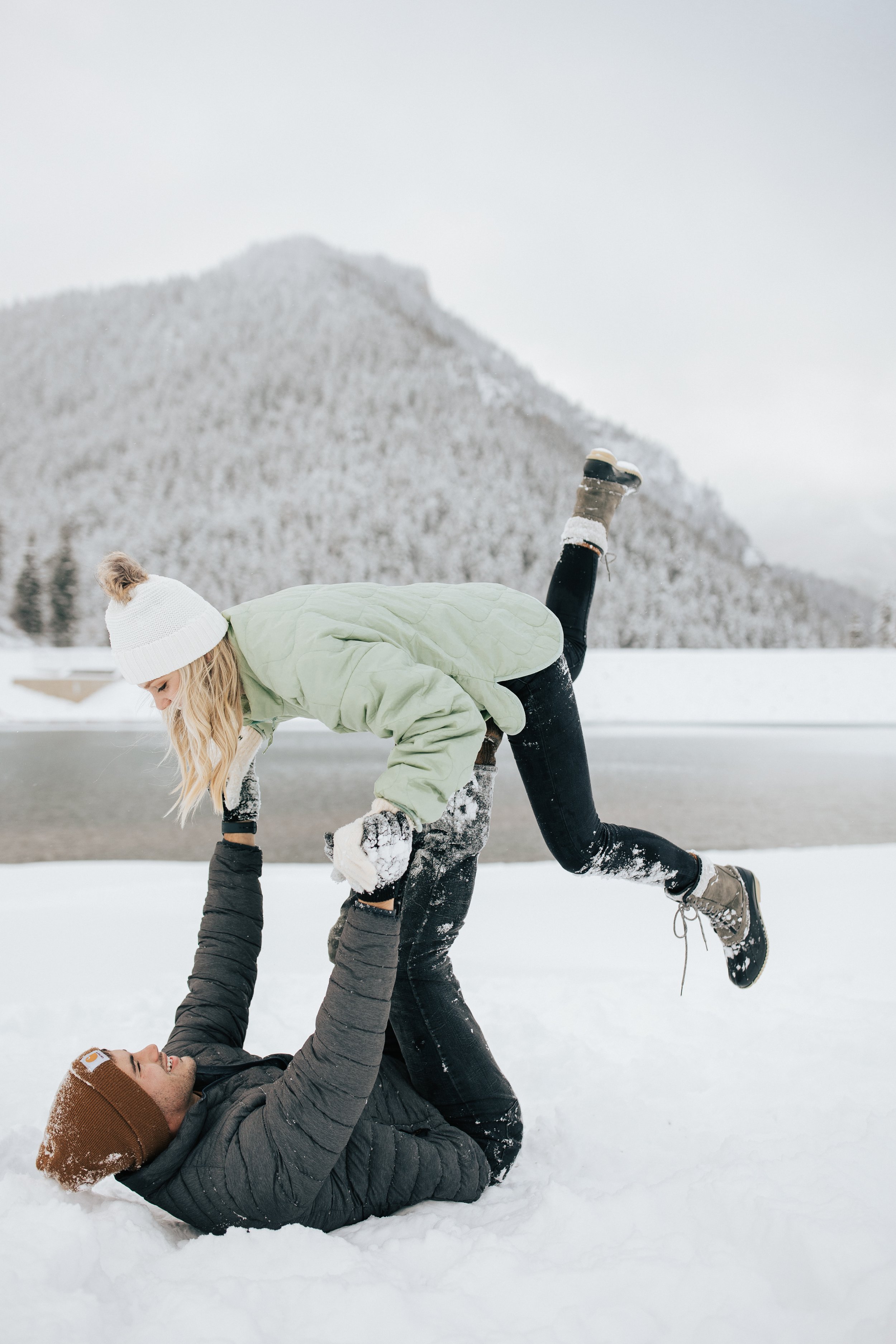  Winter photoshoot outfit inspo. Man and woman play in the snow in the mountains wearing coats and beanies. Utah mountain engagement shoot in the winter. Park City, Utah photographer. #winter #engagements #engagementsession #utahphotoshoot #utahengag
