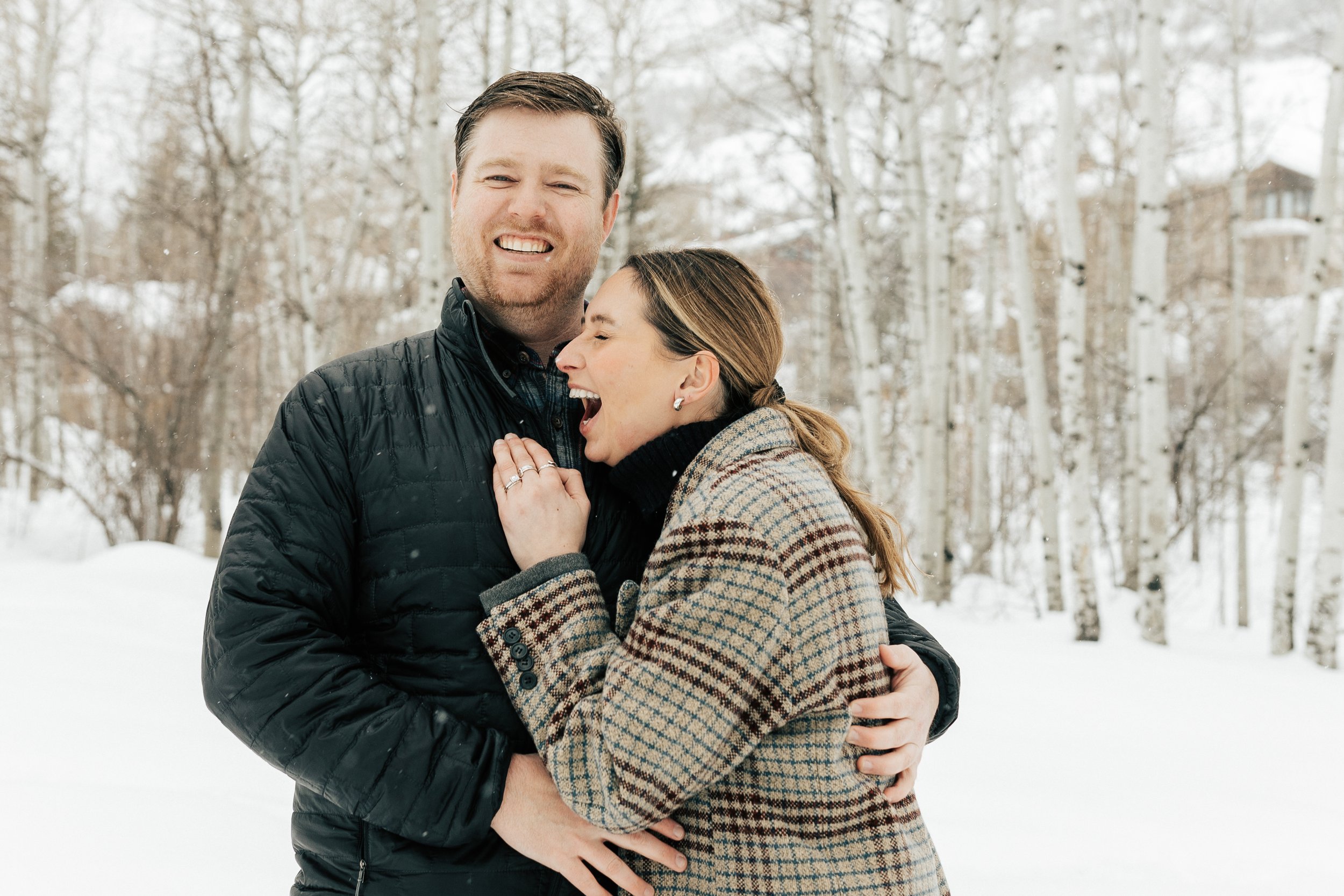  Newly engaged couple laugh and hug. Winter engagement session in Park City, Utah. Boyfriend surprises girlfriend with wedding proposal during a snowy photoshoot. Man proposes to girlfriend. #parkcity #engagements #engagementsessionn #proposal 