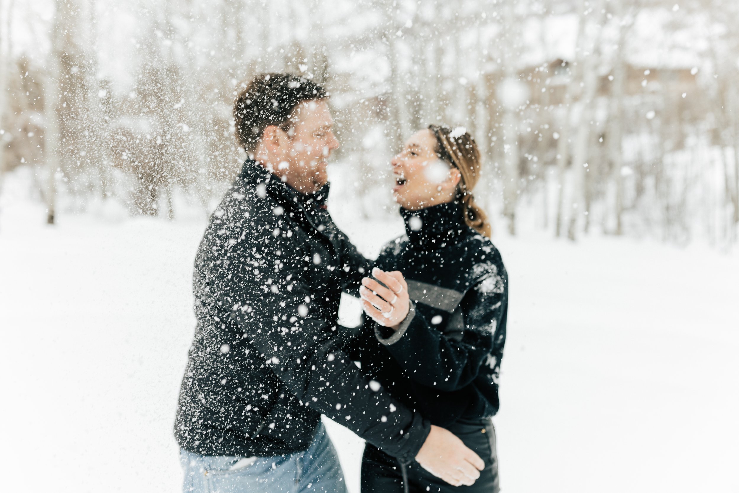  Newly engaged couple throws snow while laughing. Winter engagement session in Park City, Utah. Boyfriend surprises girlfriend with wedding proposal during a snowy photoshoot. Man proposes to girlfriend. #parkcity #engagements #engagementsessionn #pr