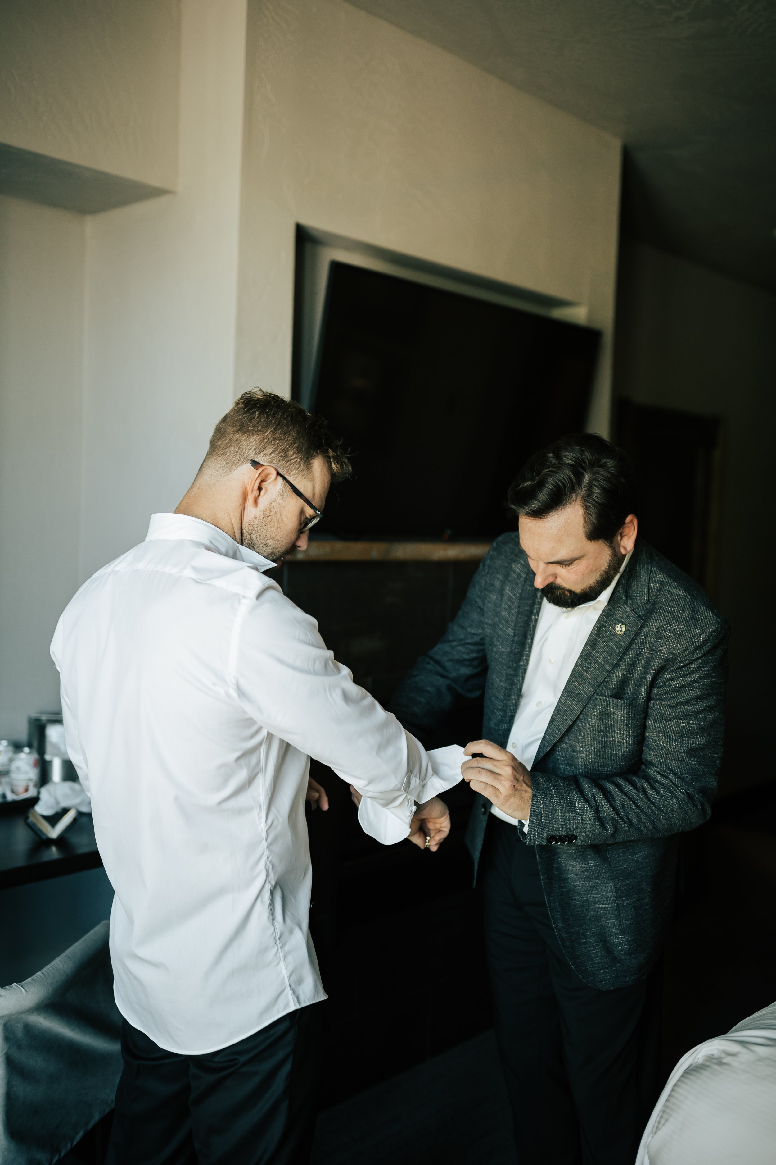  Getting ready photos. Groom gets ready in hotel room before wedding. Groomsman helps groom get ready. #montanawedding #utahwedding #gettingreadyphotos 