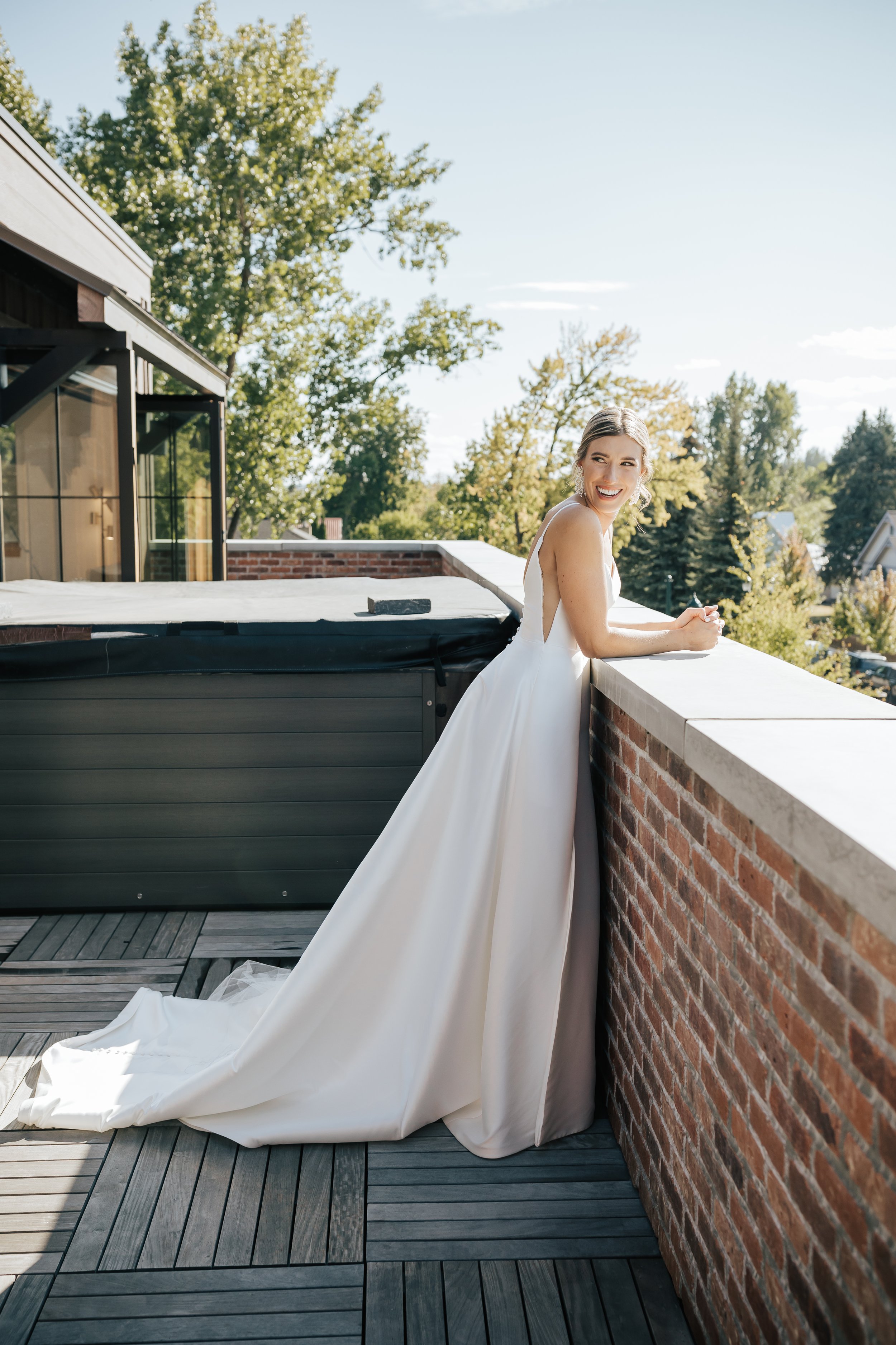 Bride looks out on hotel balcony in wedding dress before the wedding ceremony begins on a warm summer day in Whitefish, Montana. #bride #gettingready #montanawedding 
