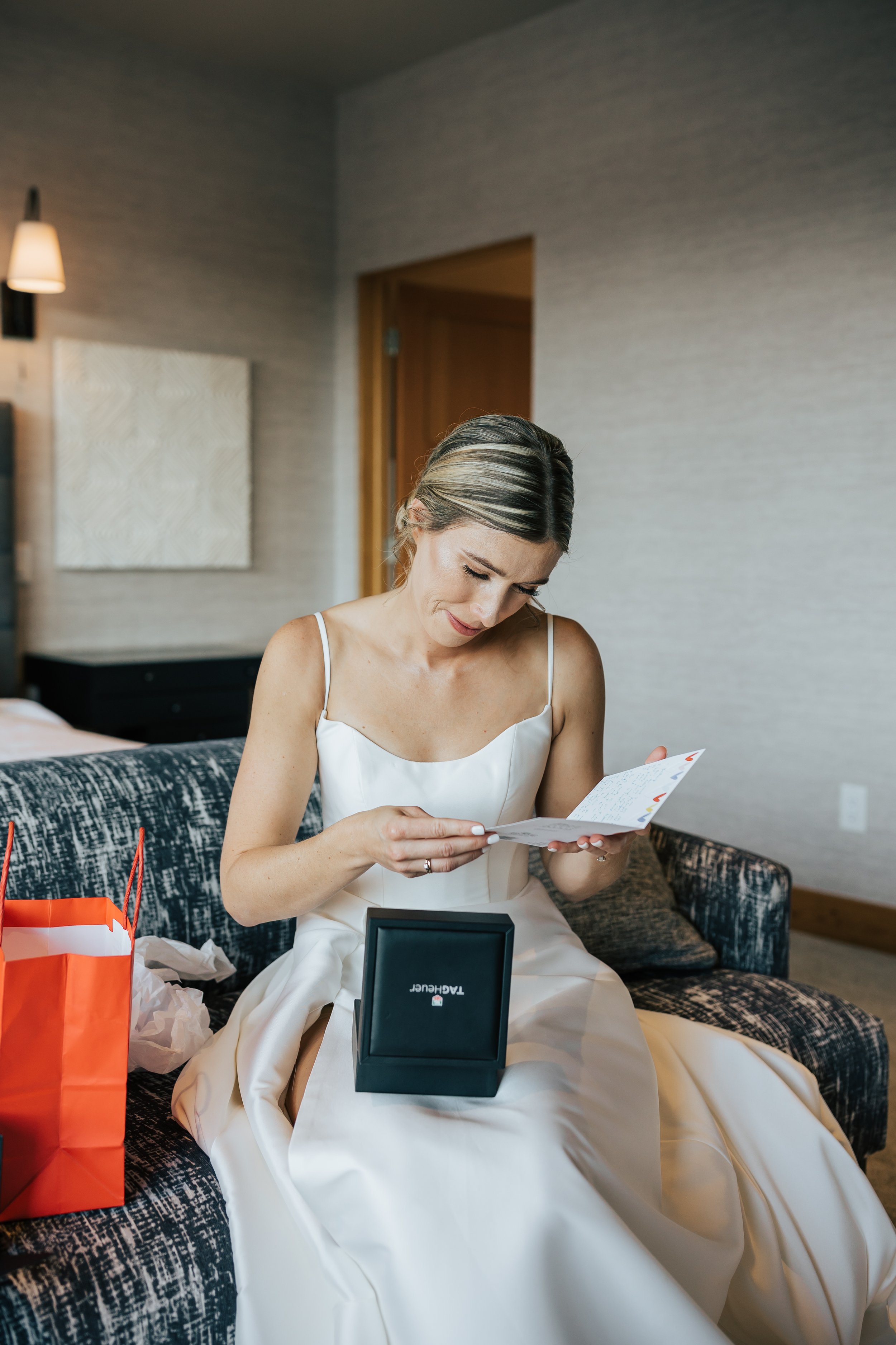  Getting ready photos. Bride gets ready in hotel room before wedding. Bride sits in wedding dress and opens gift from her groom before ceremony.  #montanawedding #utahwedding #gettingreadyphotos 