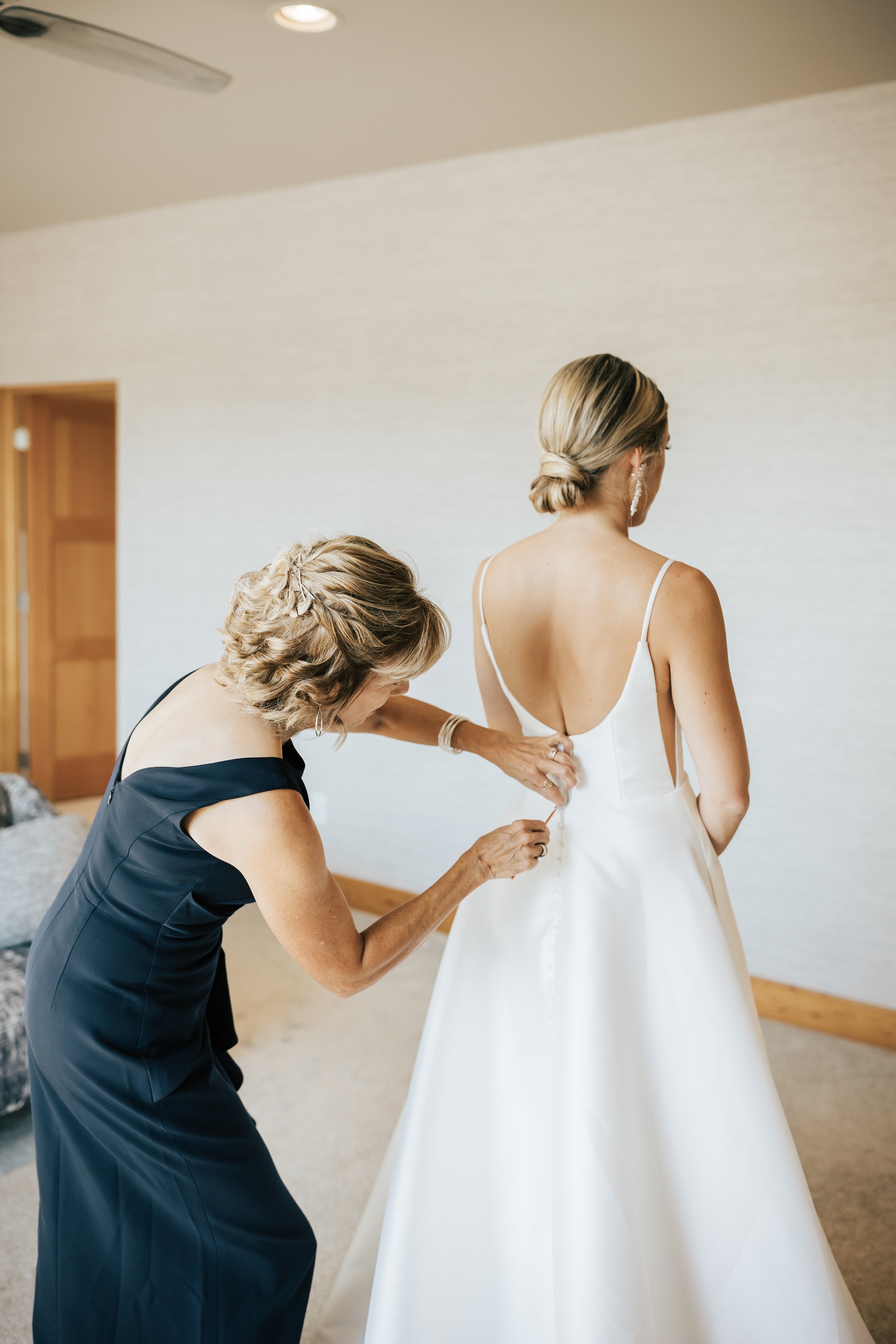  Getting ready photos. Bride’s mom helps her button up wedding dress in hotel room. #montanawedding #utahwedding #gettingreadyphotos 