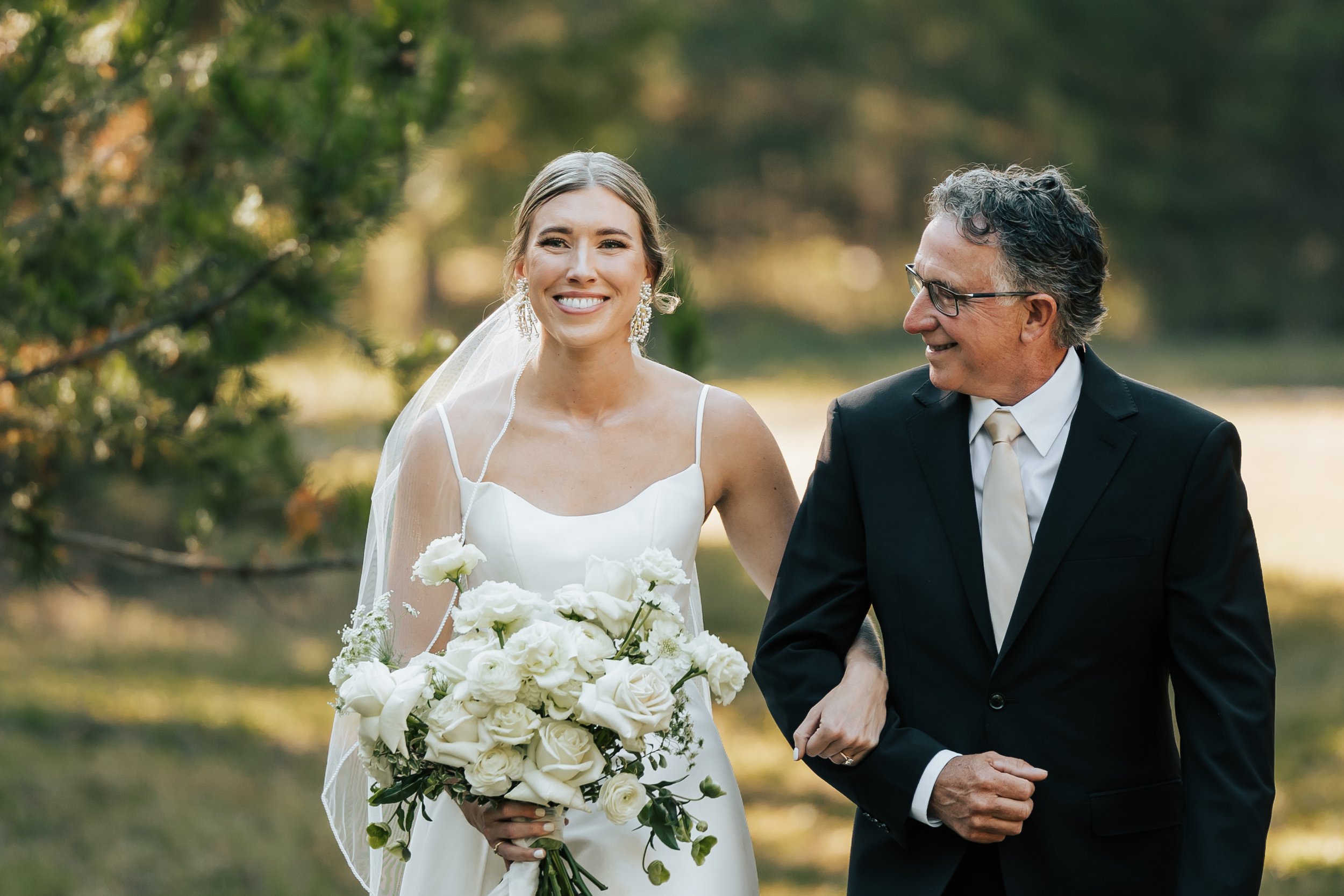  Bride and her father walk down the aisle at her Montana wedding. Father of the bride smiles at his daughter as they walk down the aisle. #montanawedding #utahphotographer #bride 