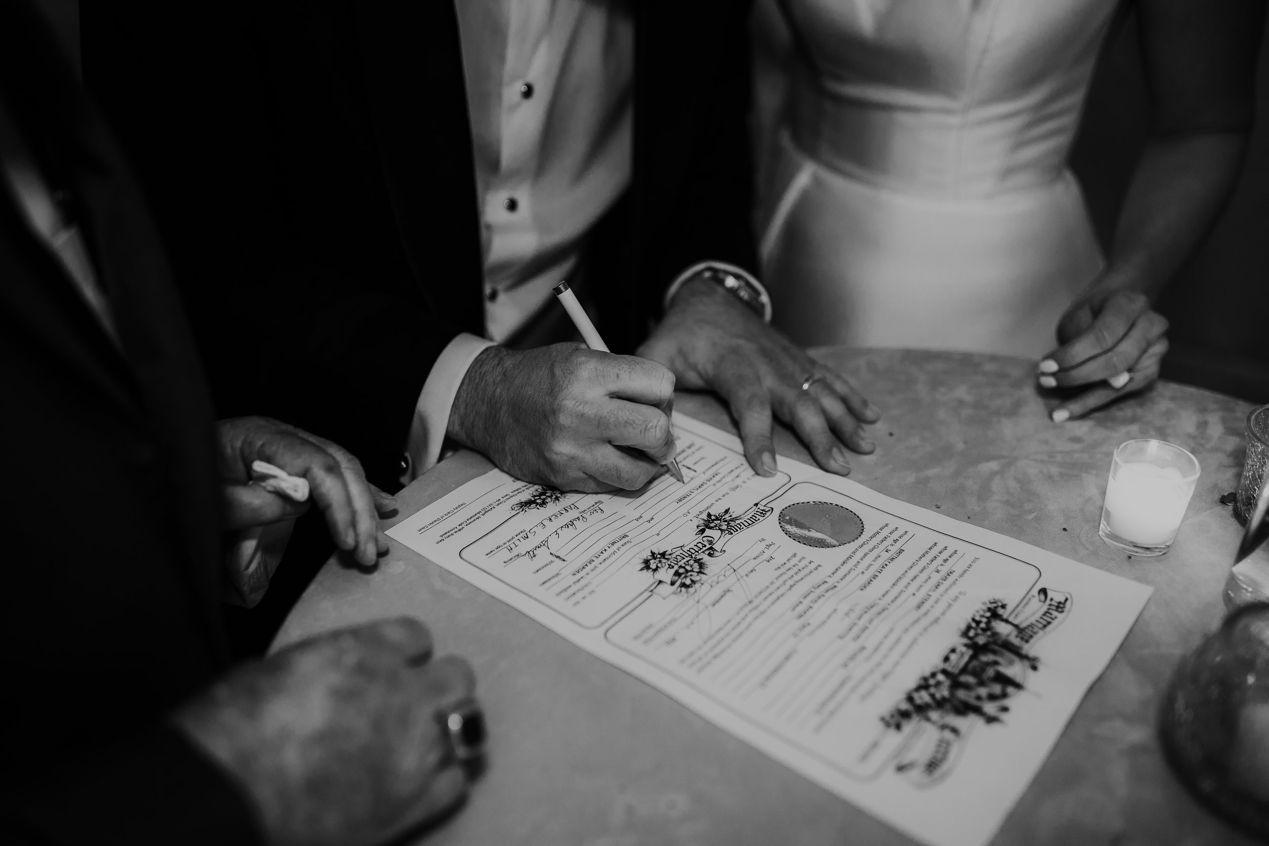  Bride and groom signing wedding certificate. Wedding inspo. Bride is wearing gorgeous large white earrings with a strappy wedding dress and veil and groom is wearing a black suit and bowtie. #montanawedding #emilyjenkinsphoto #weddingphotos #summerw