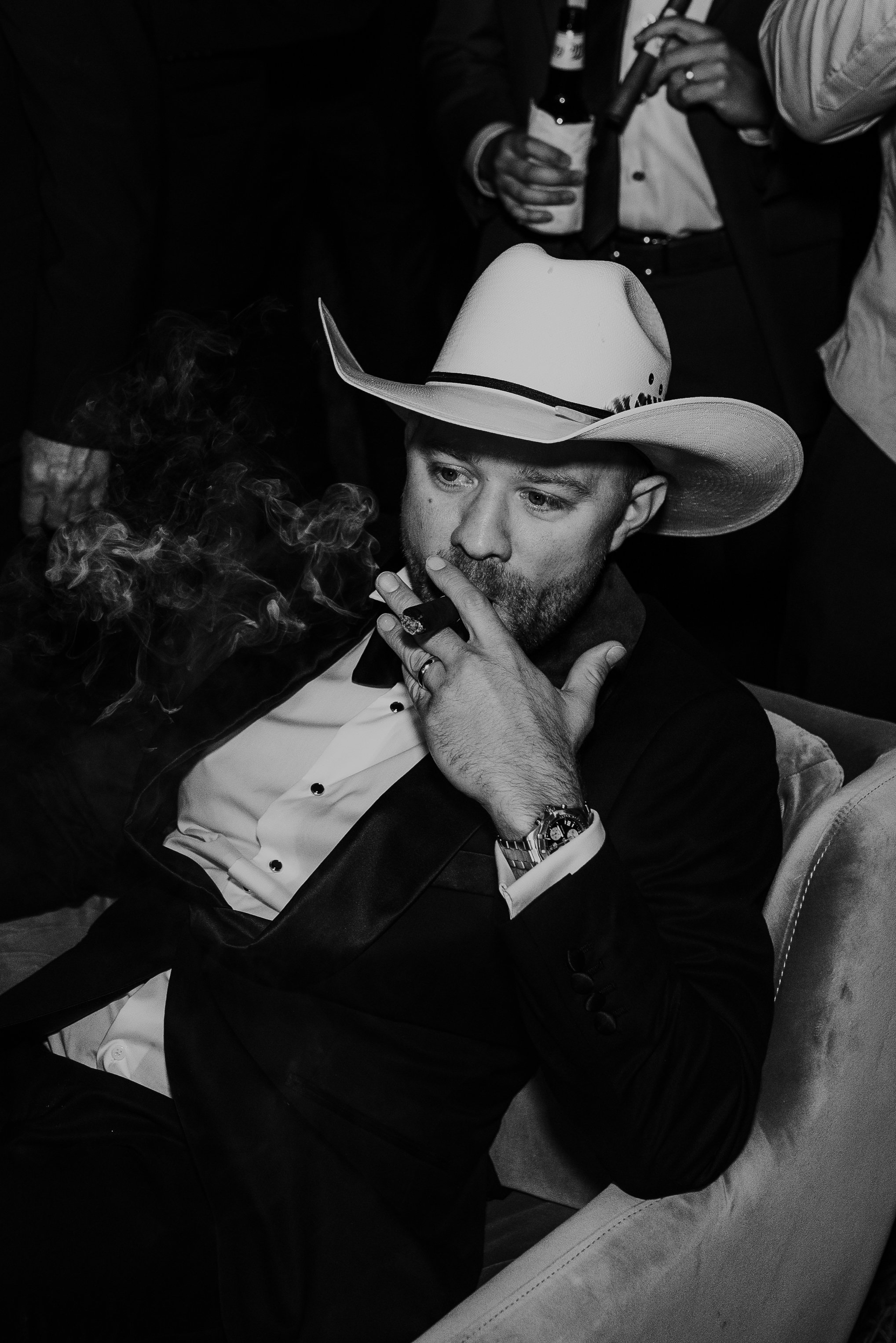  Groom smoking cigar with his groomsmen during wedding reception. Groom is wearing a cowboy hat and his suit. #montanawedding #emilyjenkinsphoto #weddingphotos #summerwedding 