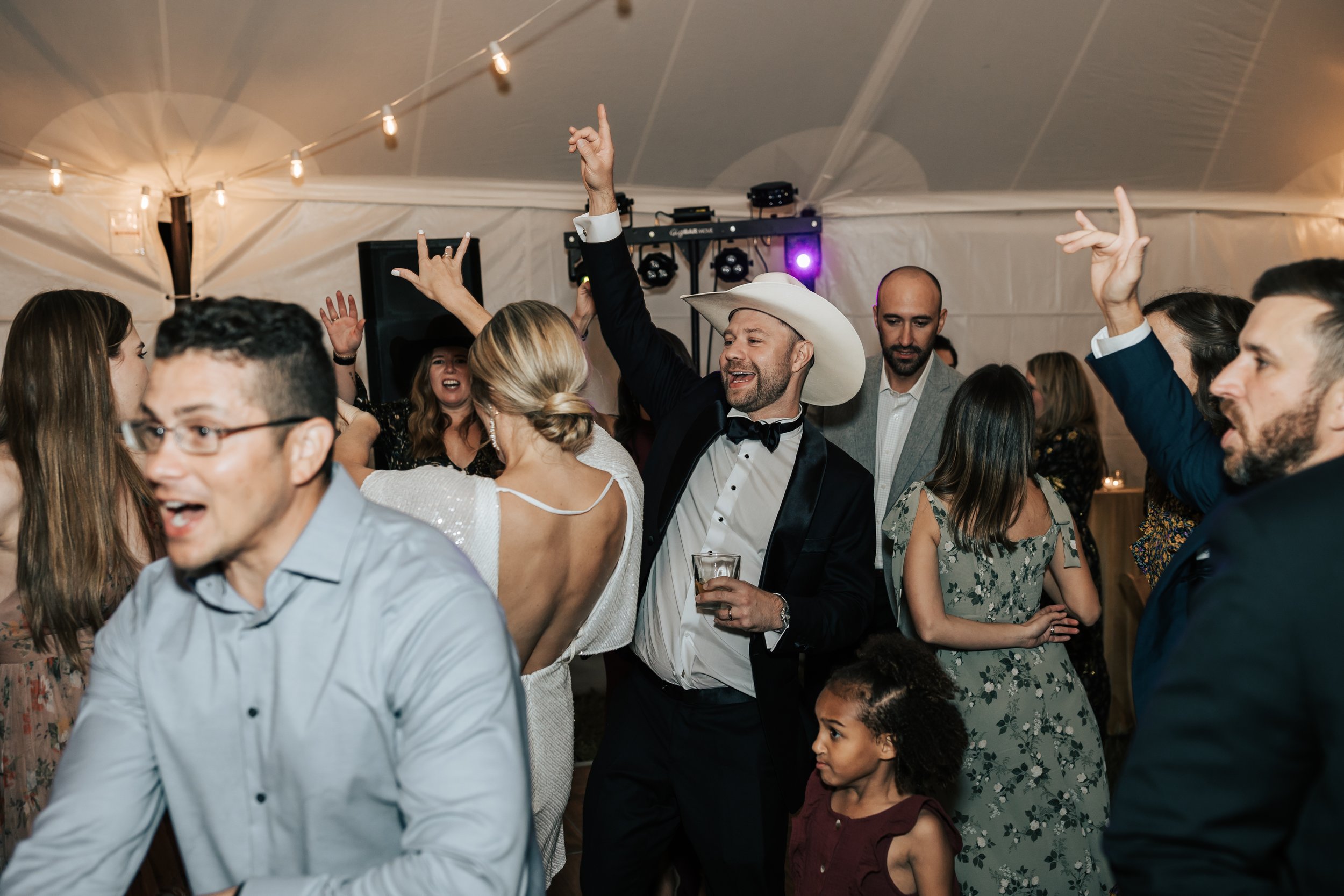  Wedding dance party. Bride and groom dance during their reception. Wedding inspo. Bride is wearing gorgeous large white earrings with a strappy wedding dress and veil and groom is wearing a black suit and bowtie. #montanawedding #emilyjenkinsphoto #