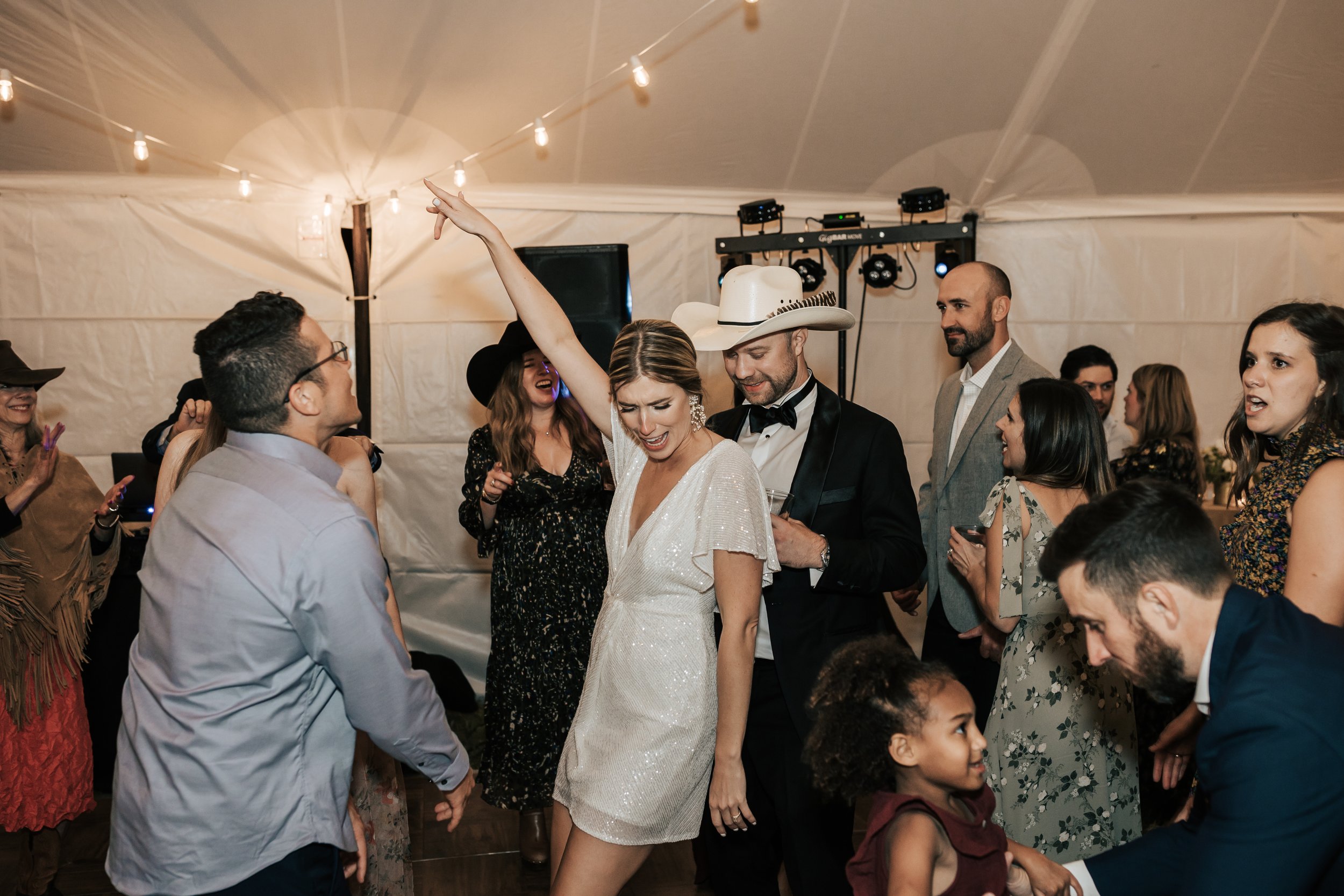  Wedding dance party. Bride and groom dance during their reception. Wedding inspo. Bride is wearing gorgeous large white earrings with a strappy wedding dress and veil and groom is wearing a black suit and bowtie. #montanawedding #emilyjenkinsphoto #