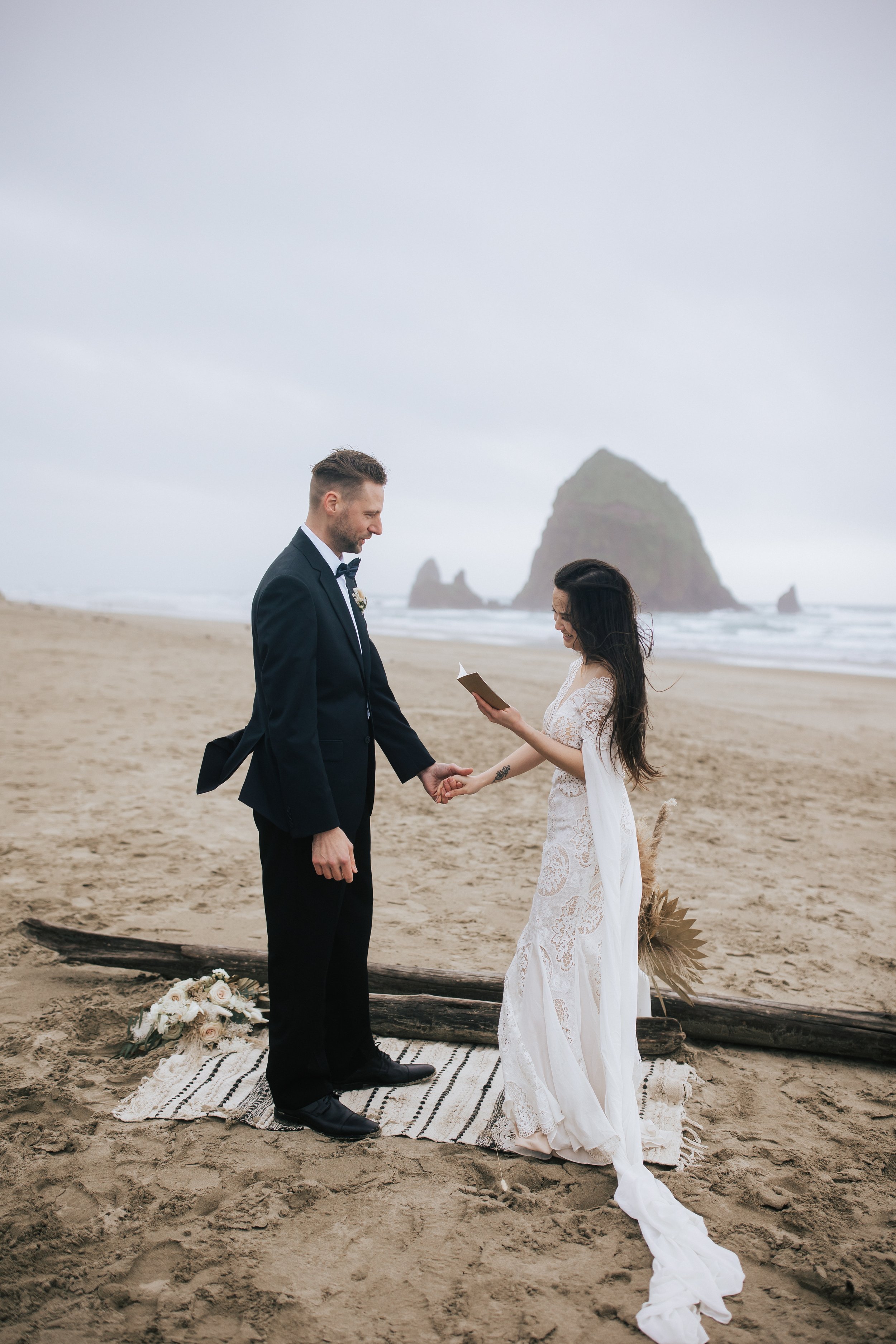  Bride reads her vows to the groom in this boho beach elopement at cannon beach in Oregon by pacific northwest elopement photographer emily jenkins photo learn how to get stunning wedding photos like this from your pnw elopement #pnw #pnwwedding #pnw