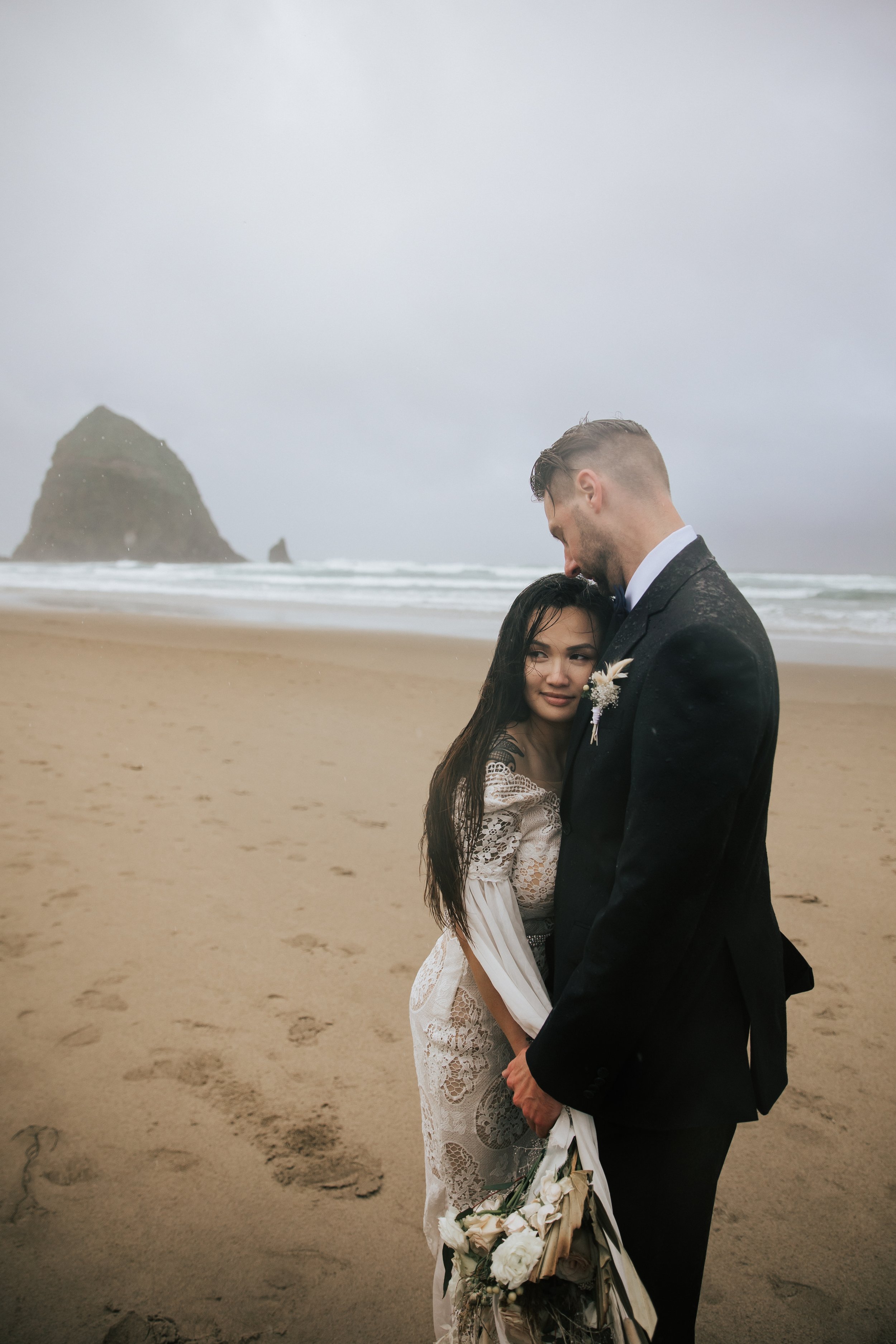  Bride and groom stand close together on cannon beach near seaside oregon elopement photography in the pacific northwest by emily jenkins photo professional elopement pictures bohemian bride #pnw #pnwwedding #pnwelopement #cannonbeach #cannonbeachelo