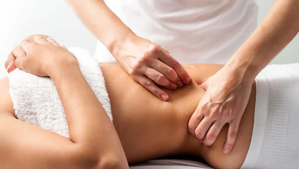 Una persona riceve un massaggio alla schiena in un ambiente di spa o fisioterapia.