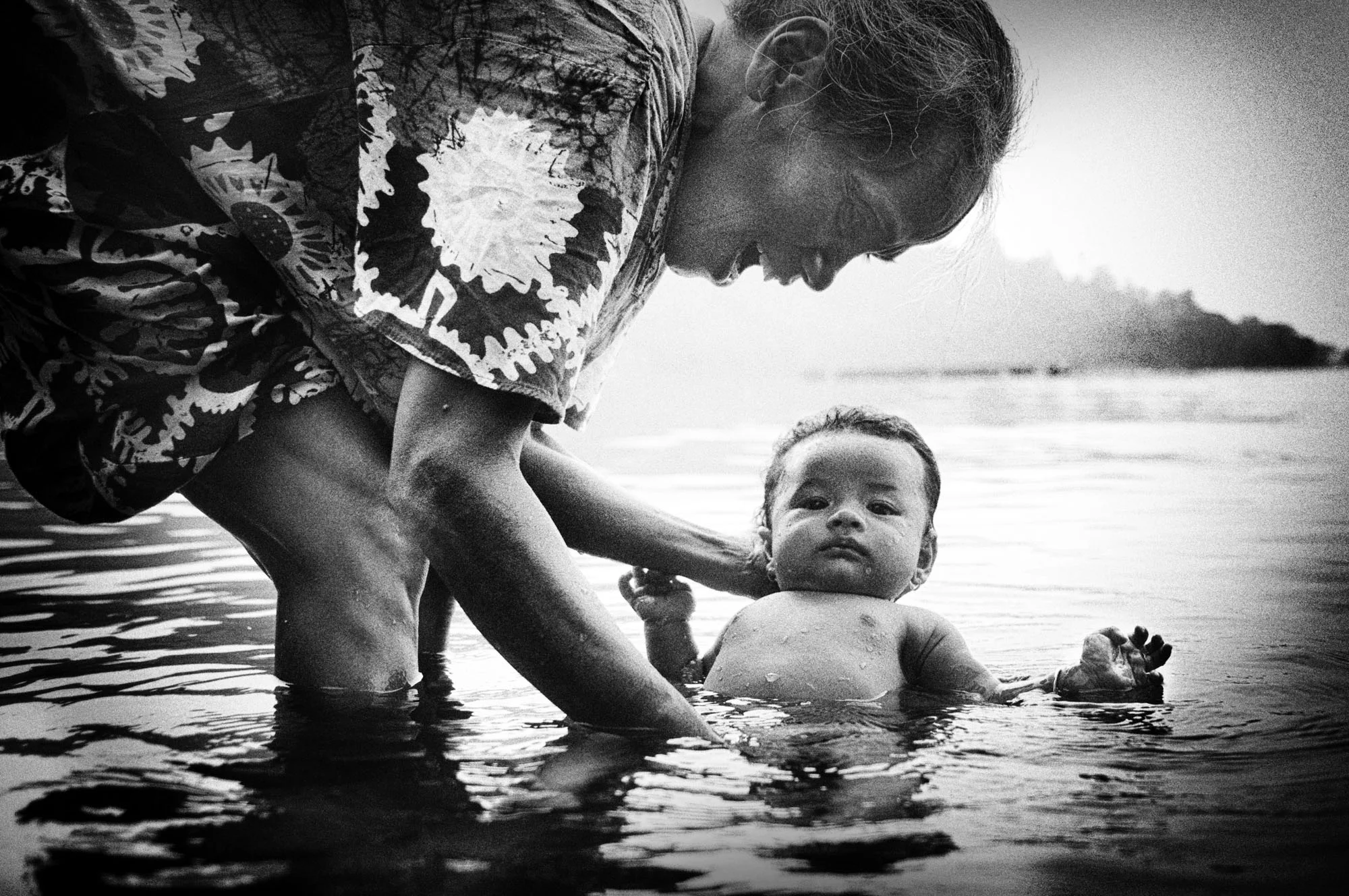 Sasmiati and her granddaughter begin their da by bathing on the edge of the lake. Her daughter’s family homecoming fills her house with happiness.