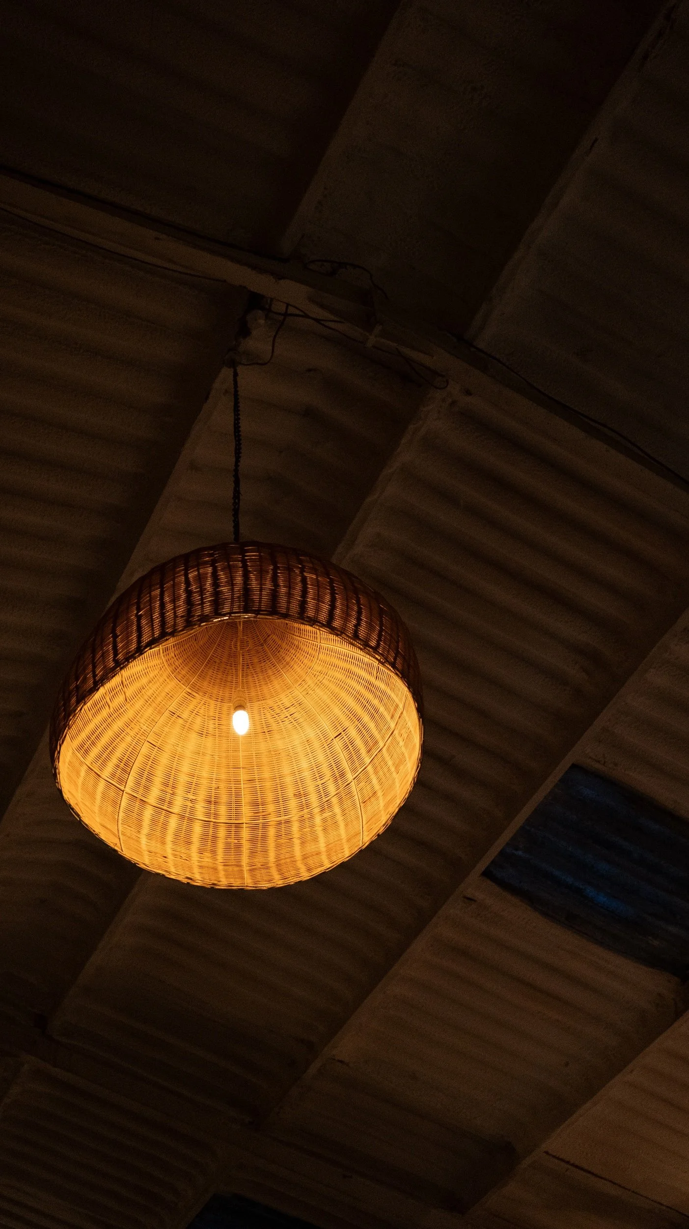 Warm yellow pendant light hanging from a ceiling with wooden panels.