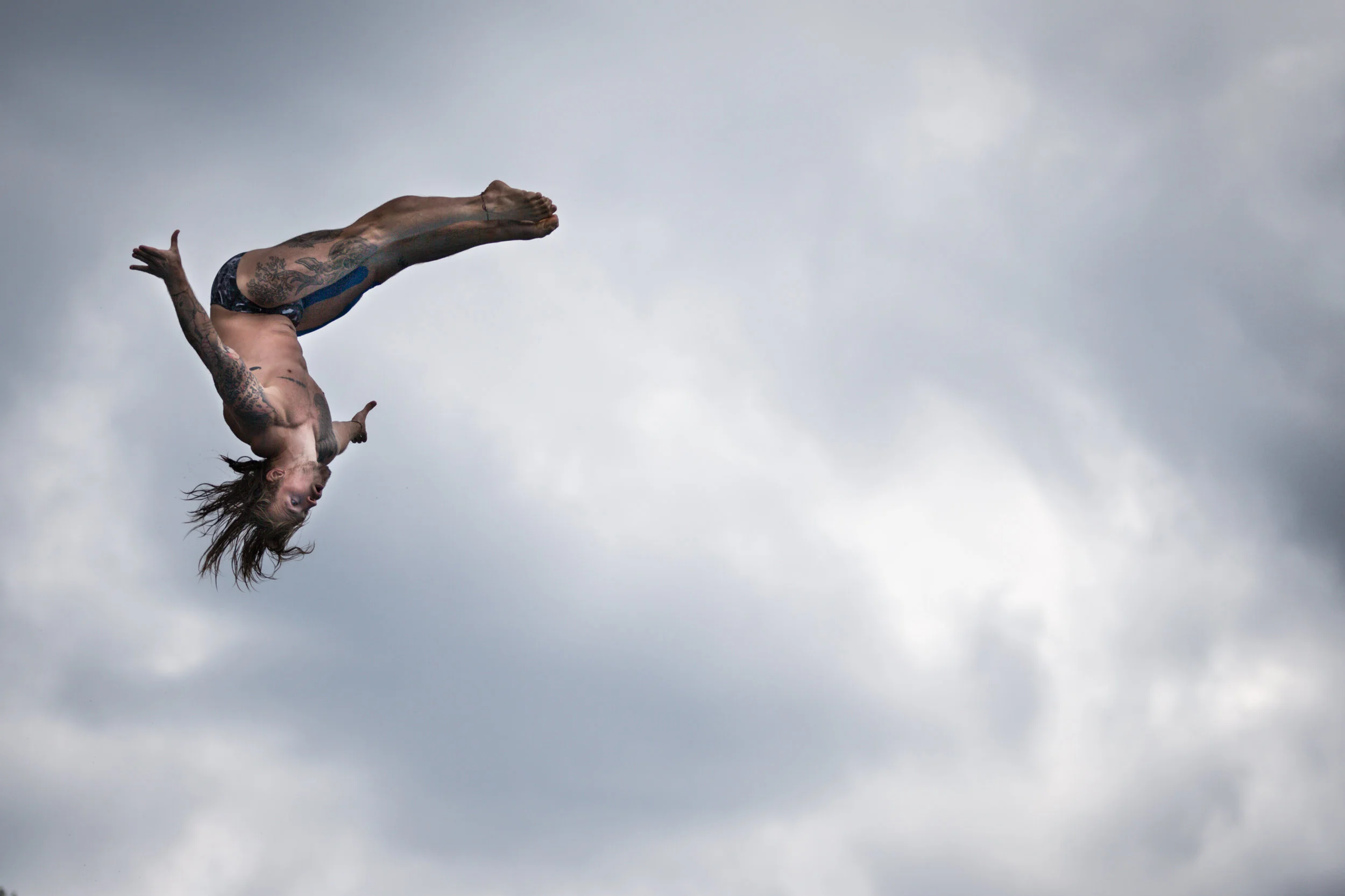 Matthias Appenzeller, Teilnehmer der «Cliff Diving World Series», zeigt bei einem Workshop vor Wolkenkulisse einen Sprung im Freibad Oberdorf in Dübendorf am 10. Juli 2018.