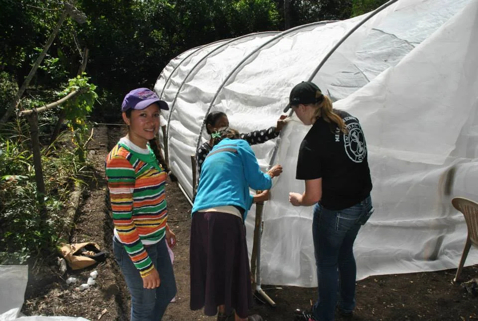 Namlo Field Coordinator Rosario Velasques, international volunteer help a local family build a greenhouse in Nicaragua.