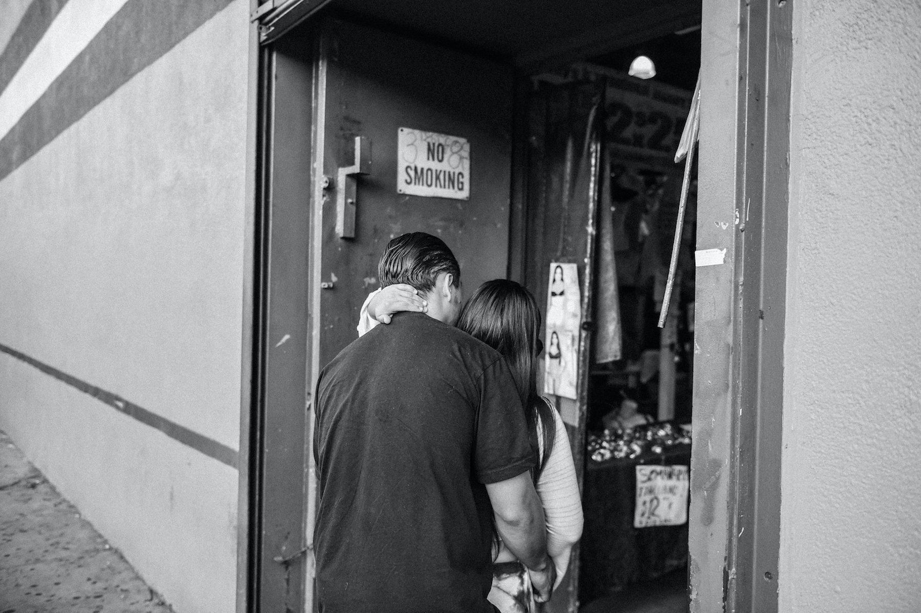  A couple embracing each other as they step into the El Faro Plaza, one of Los Angeles’s most bustling indoor swap meets since the 1970s. This is from a personal project of almost 10 years that documents the city's cultural outdoor and indoor swap me