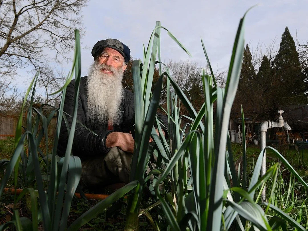 John Fischer sits with leeks in his garden on Feb. 26, 2026, in Eugene, Oregon. Despite the winter lull in produce, Fischer still eats from his garden every day. He explains how healthy vegetable gardens begin below the surface, where soil microorgan
