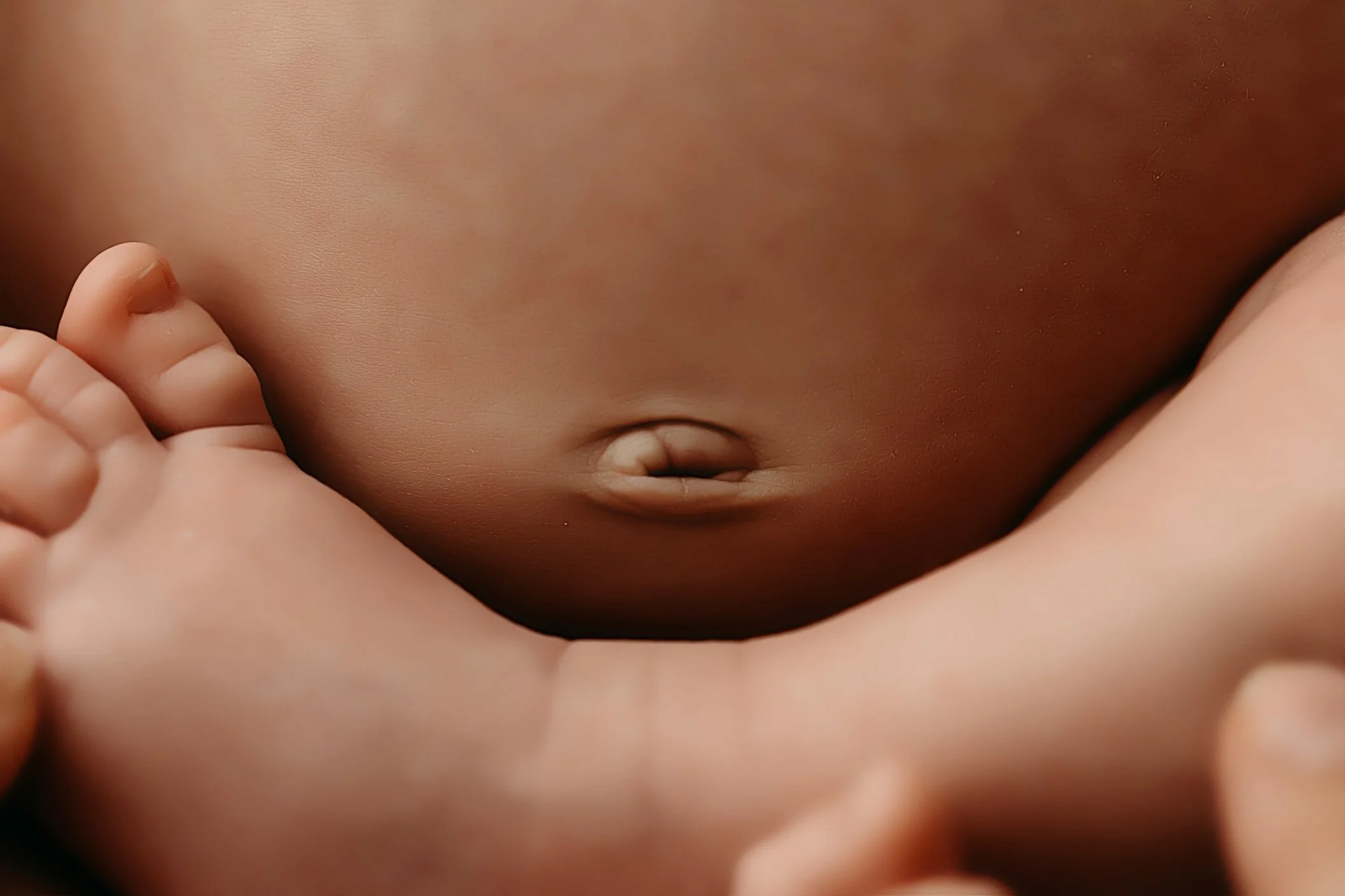 Close-up of a baby doll's torso with a hand touching its belly.