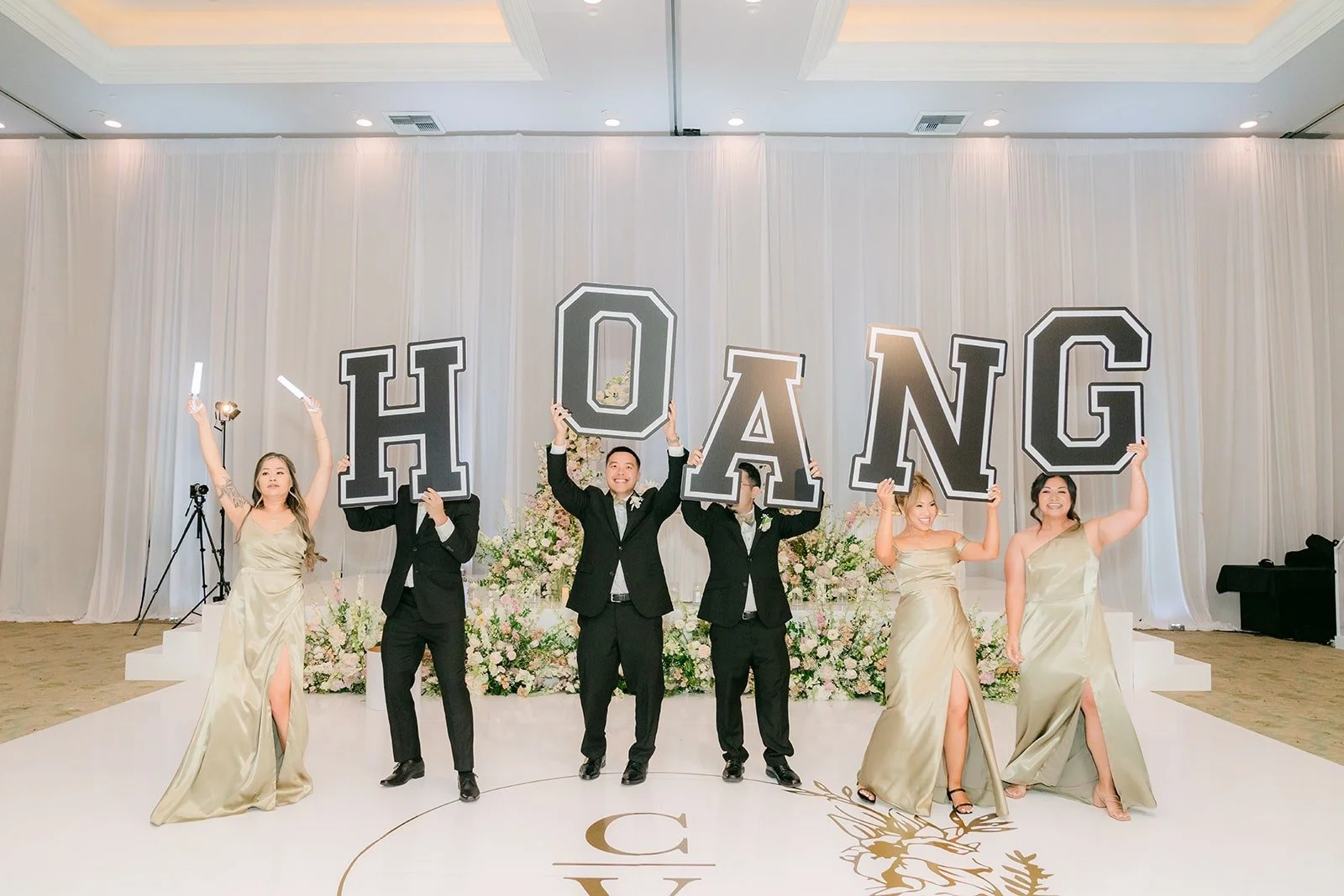 The wedding party lined up with the HOANG letters