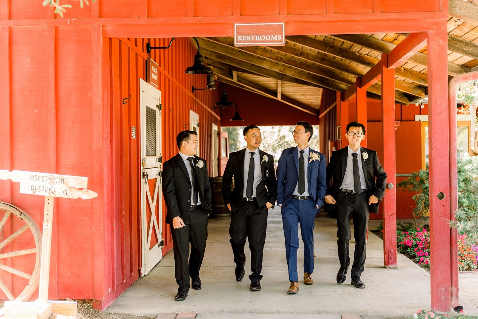 Alex and his groomsmen walking under the barn's red beams