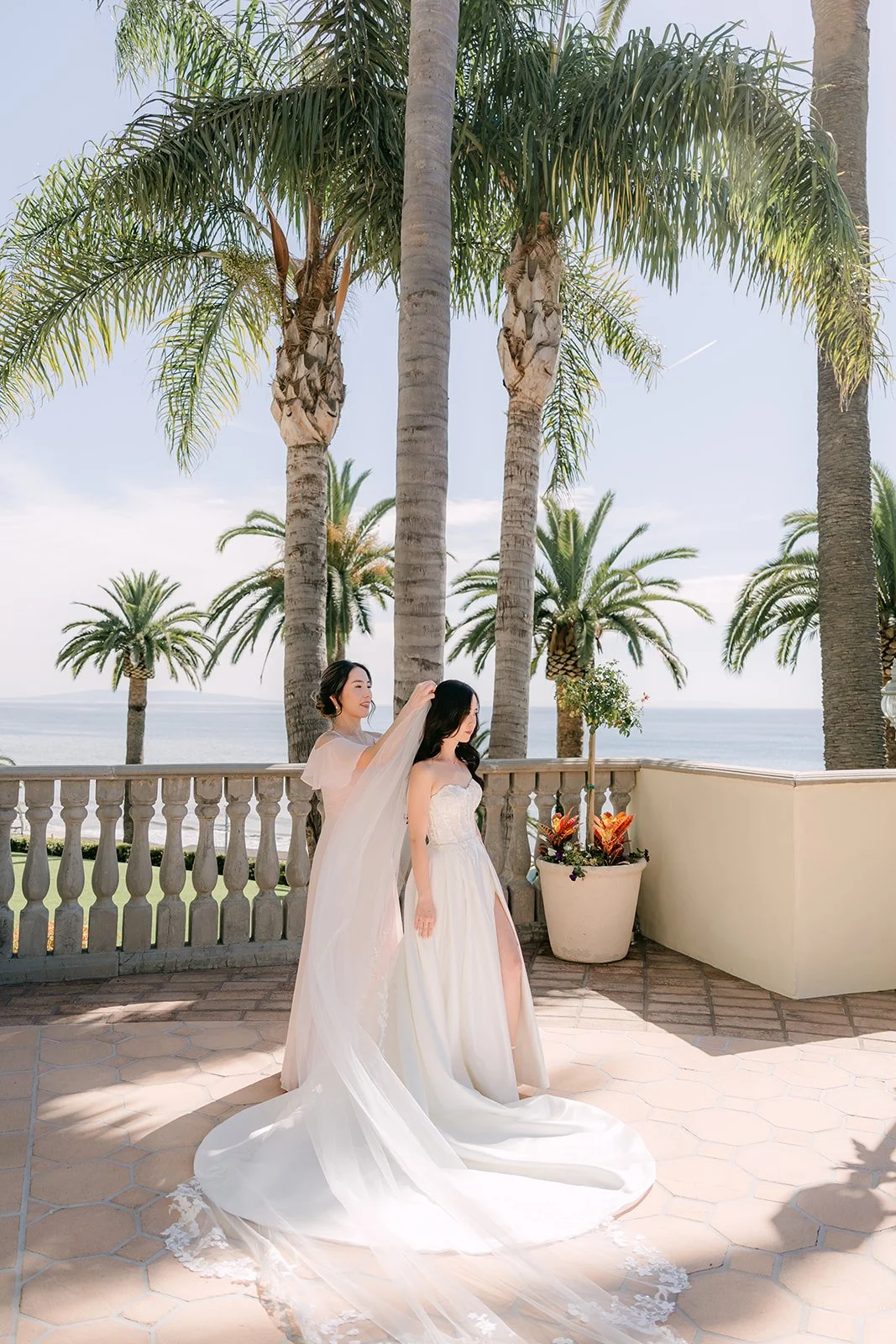 Bridesmaid fluffing the bride's train on the terrace