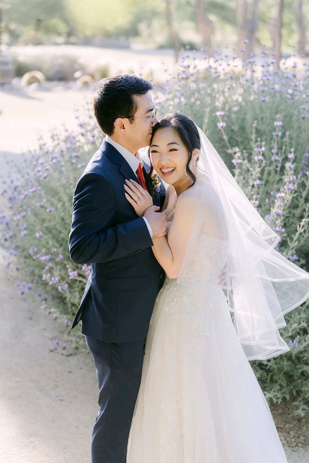 Bride resting her head on the groom's shoulder as her veil catches the breeze