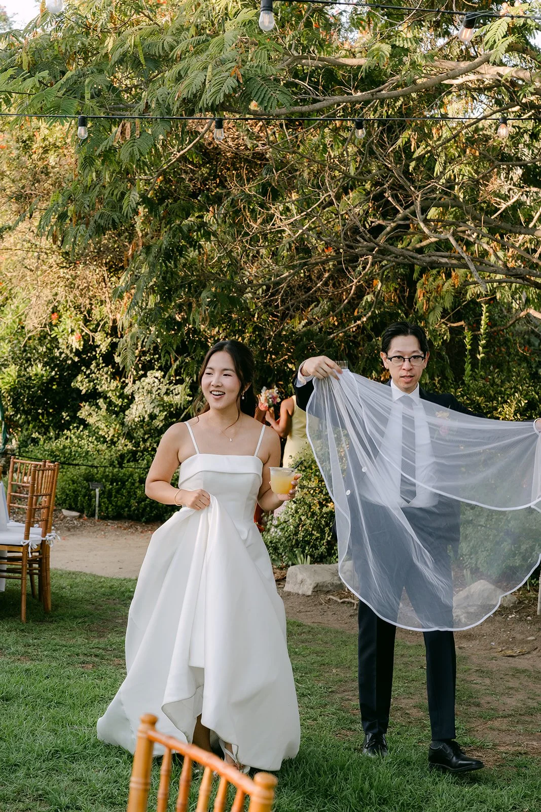 Leroy playfully fanning out Saya's veil between the tables