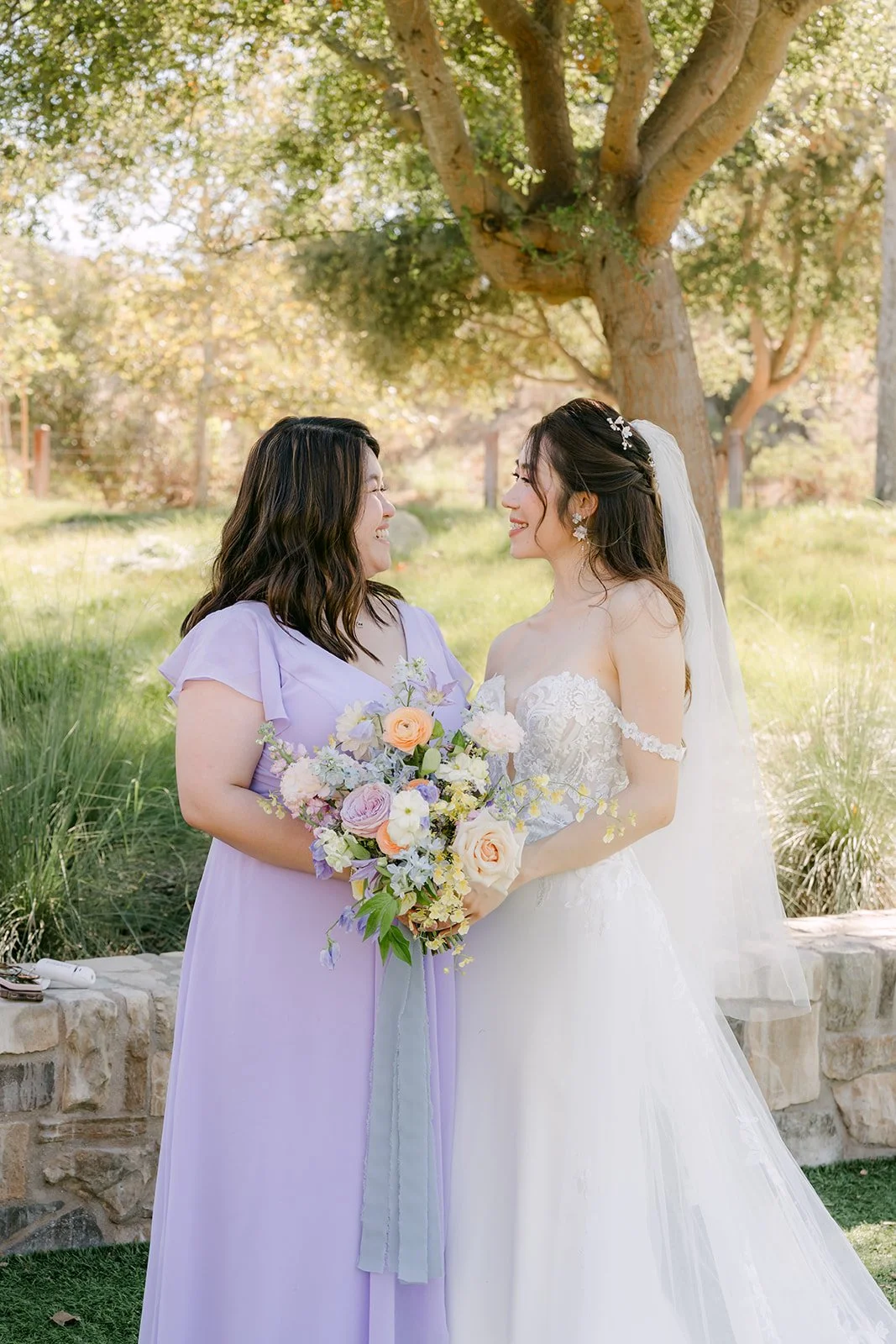 Christie sharing a laugh with a bridesmaid in a lilac dress.
