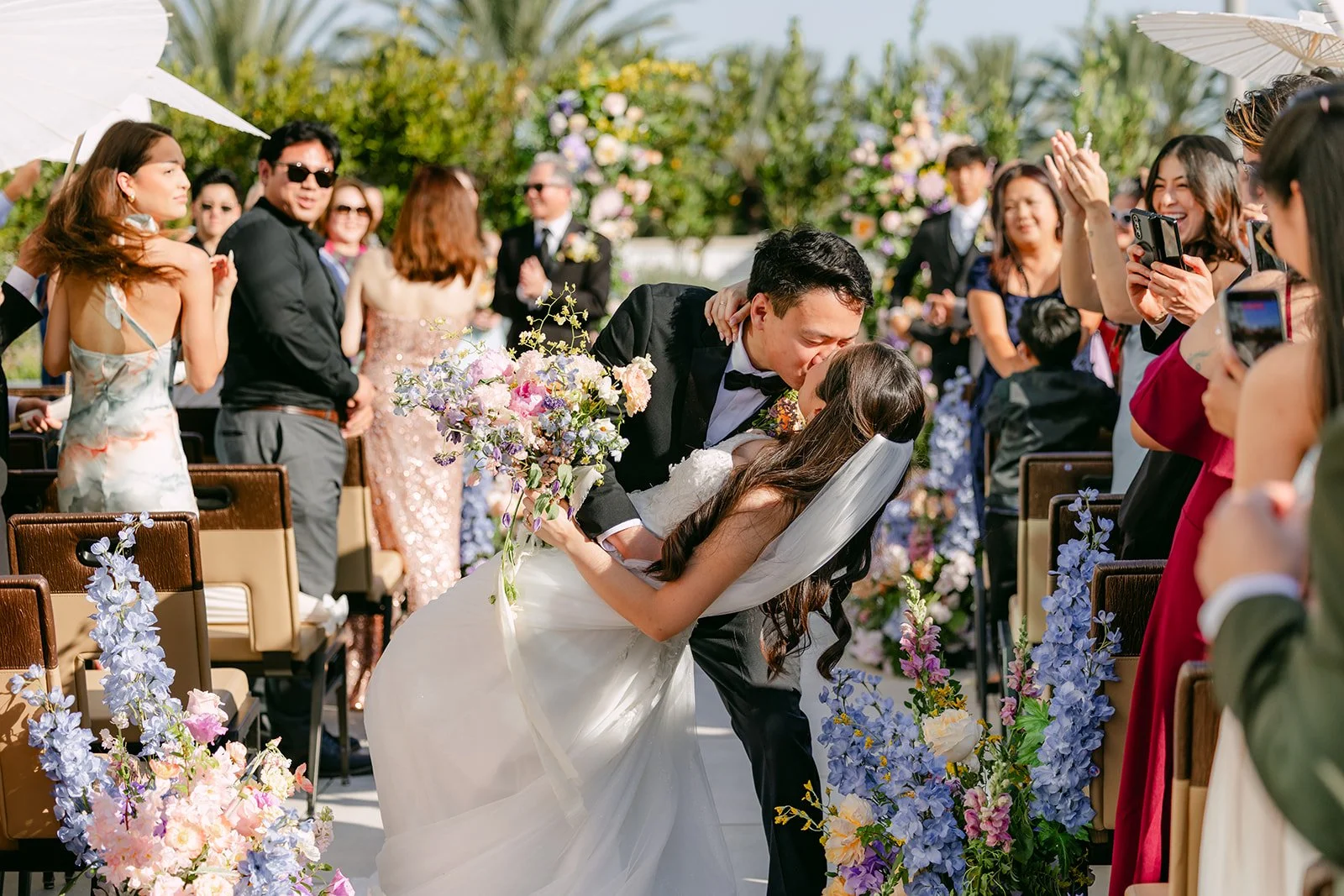 Groom dipping the bride for a kiss as guests cheer in the aisle