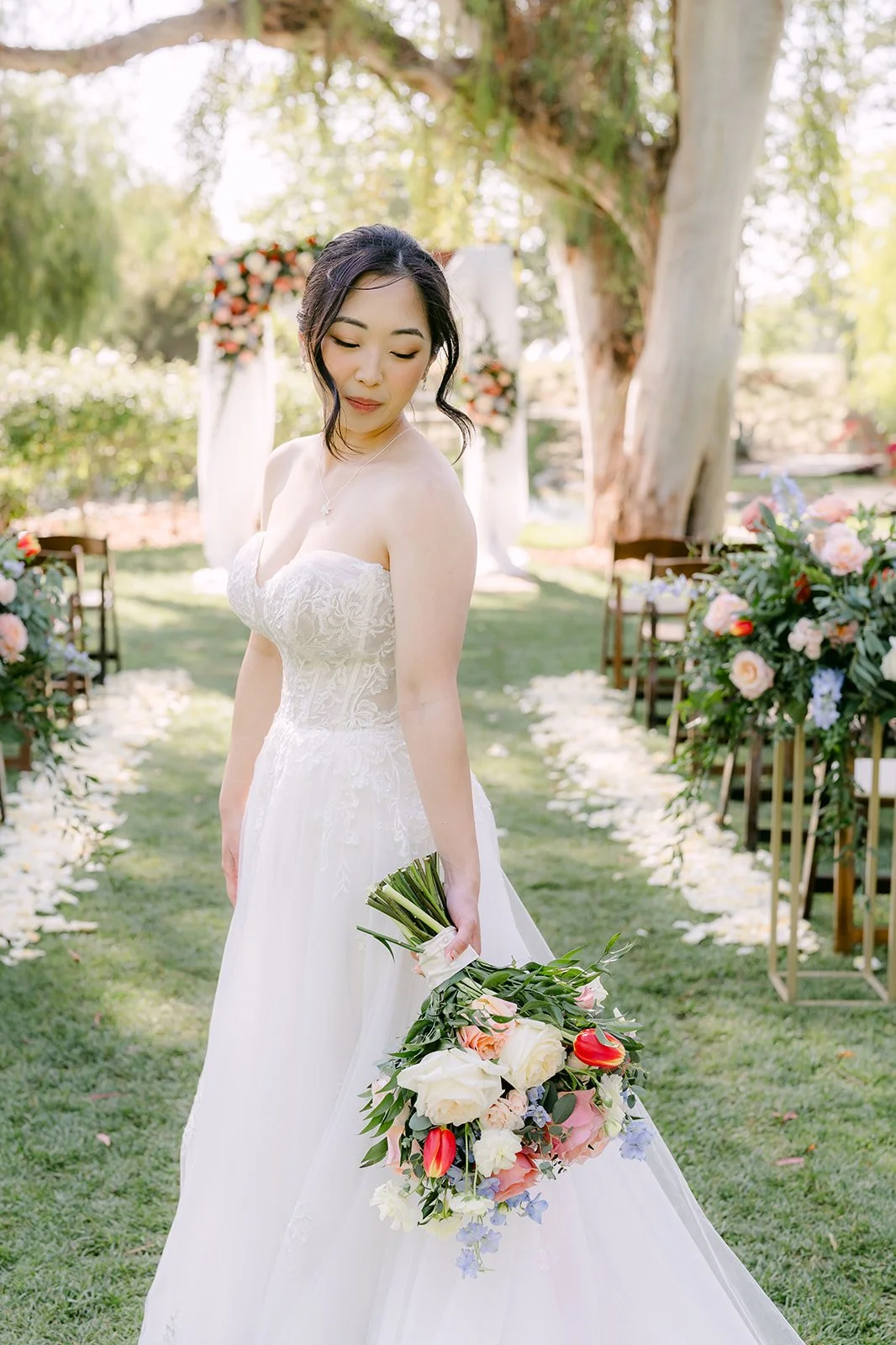 Yishan walking down the empty ceremony aisle with her bouquet at Galway Downs
