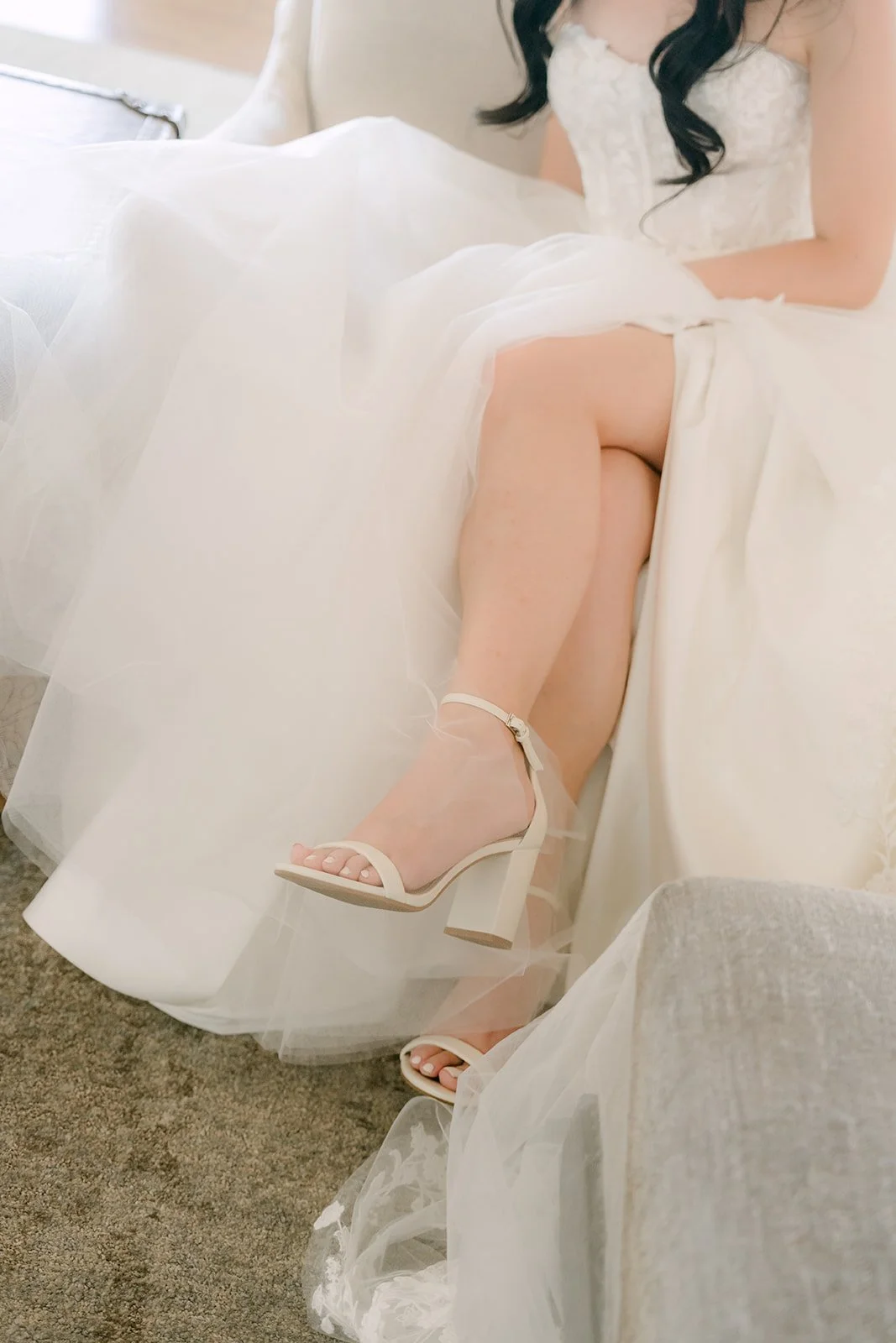 Bride's strappy heels peeking out from her gown