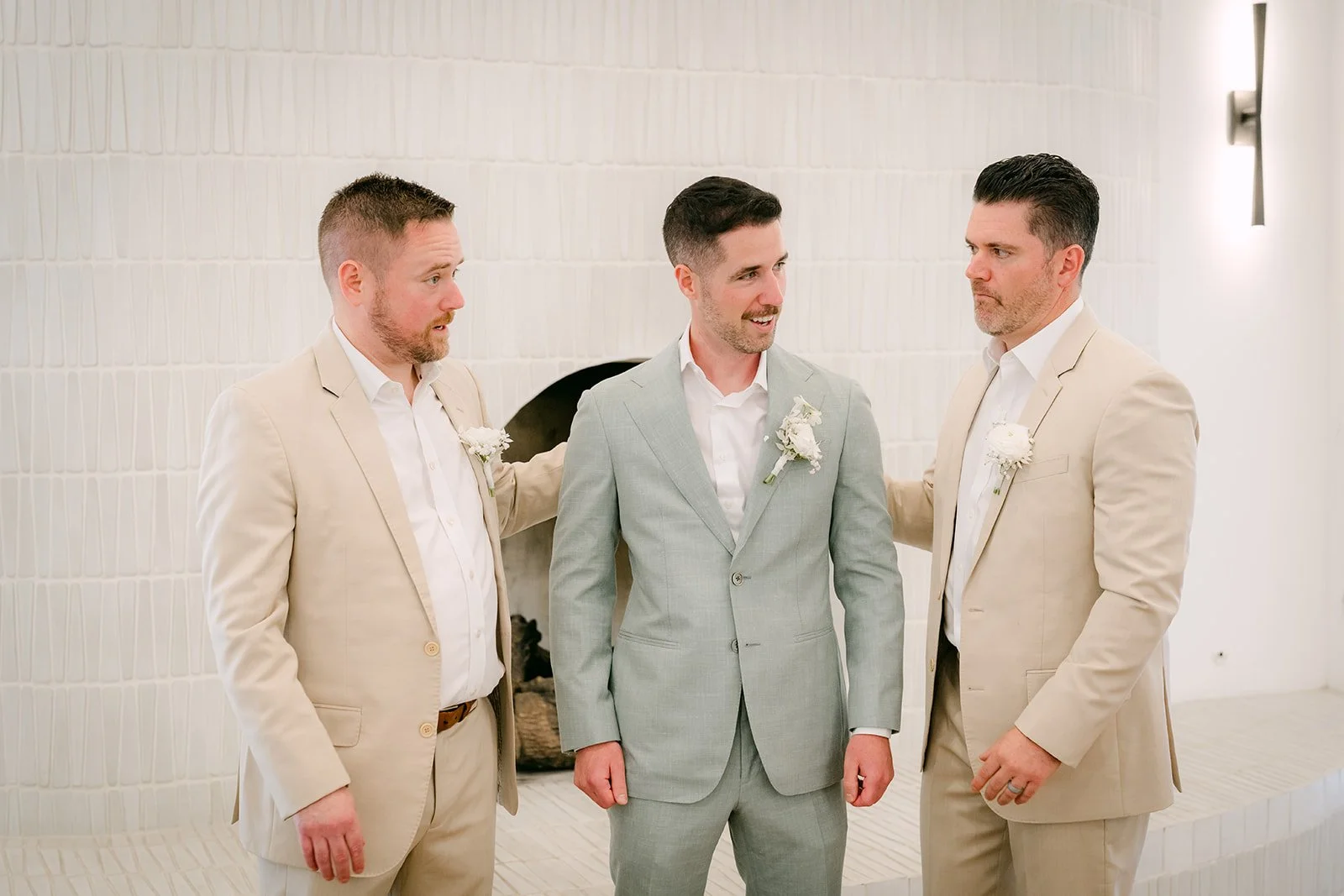 Anthony in a sage suit with two groomsmen in sand linen in the groom's room